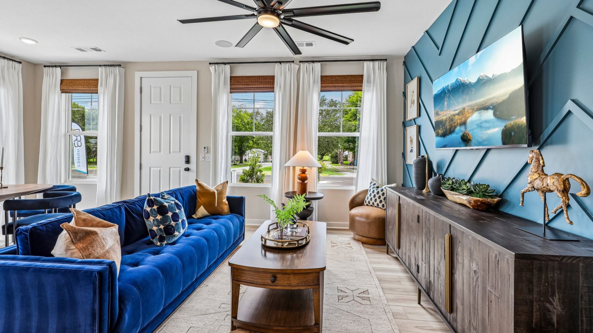 Gathering room with ceiling fan, hard surface flooring, and accent wall