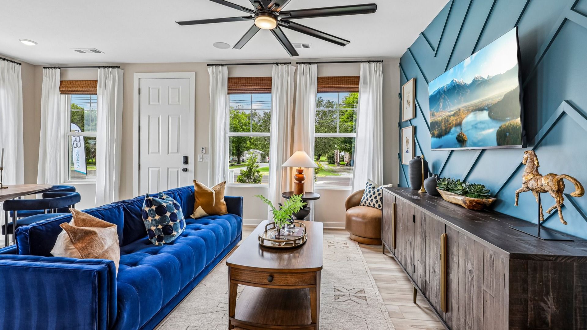Gathering room with accent wall, ceiling fan, and windows