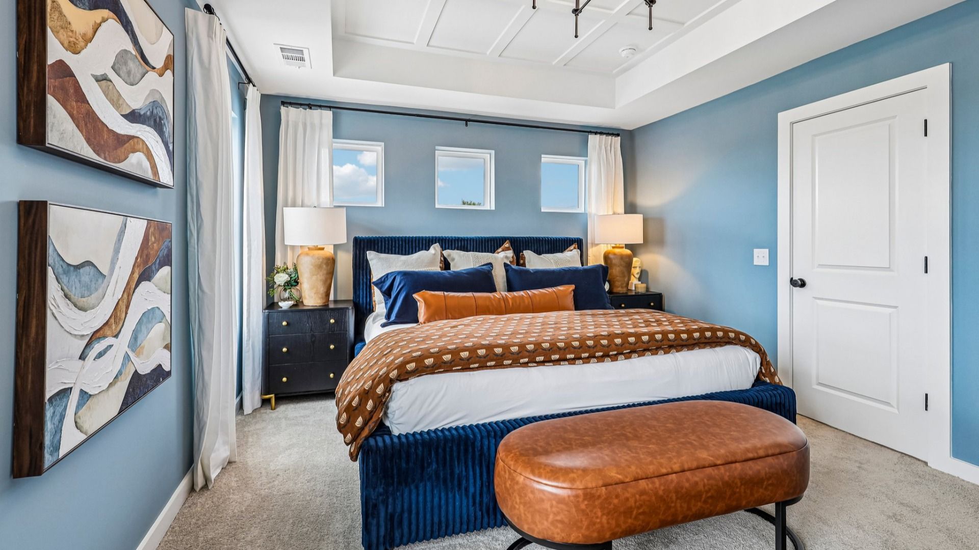 Primary suite with tray ceiling, carpet, and windows