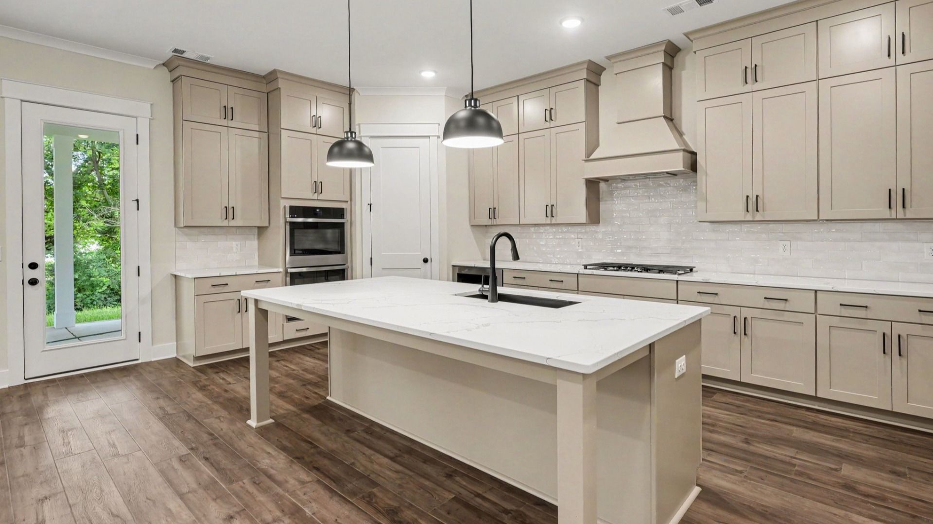 Kitchen with quartz countertops, tile backsplash, and light cabinetry