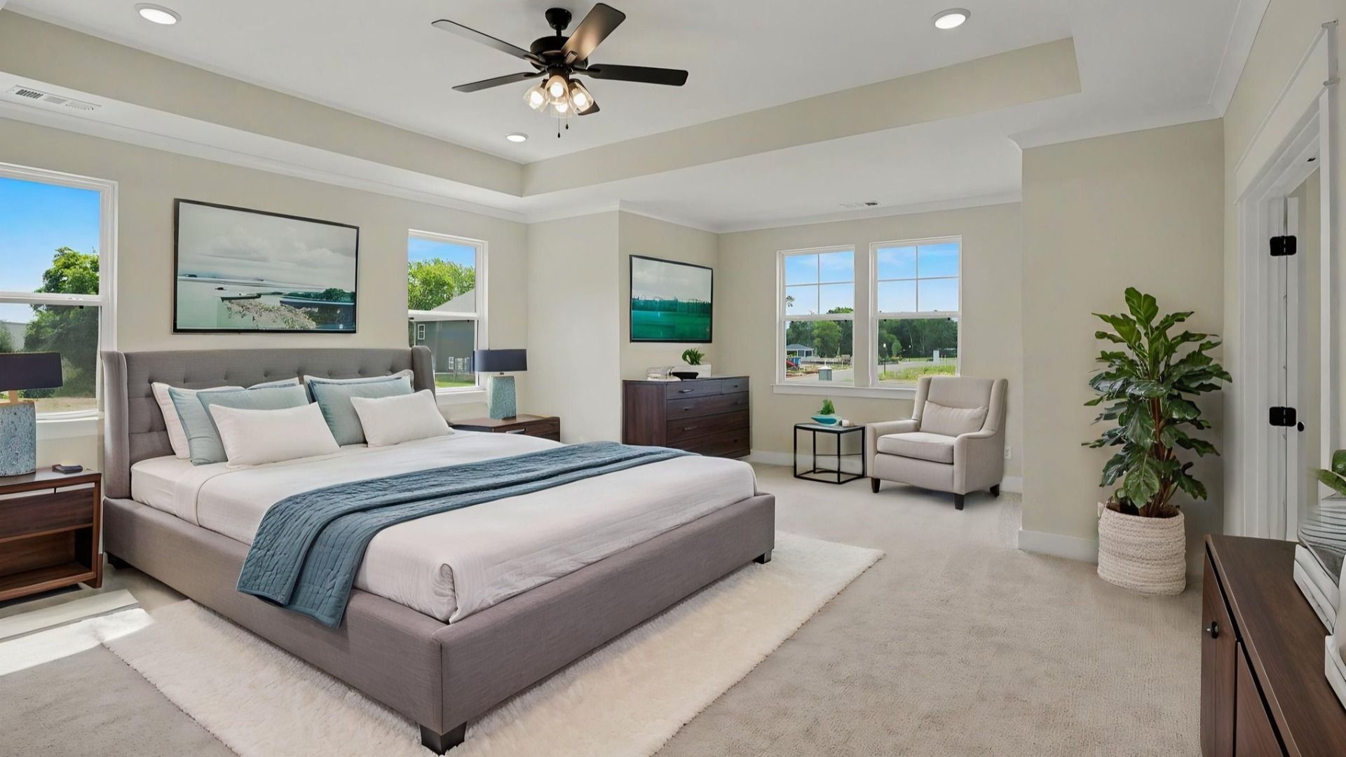 Primary suite with tray ceiling, ceiling fan, and carpet