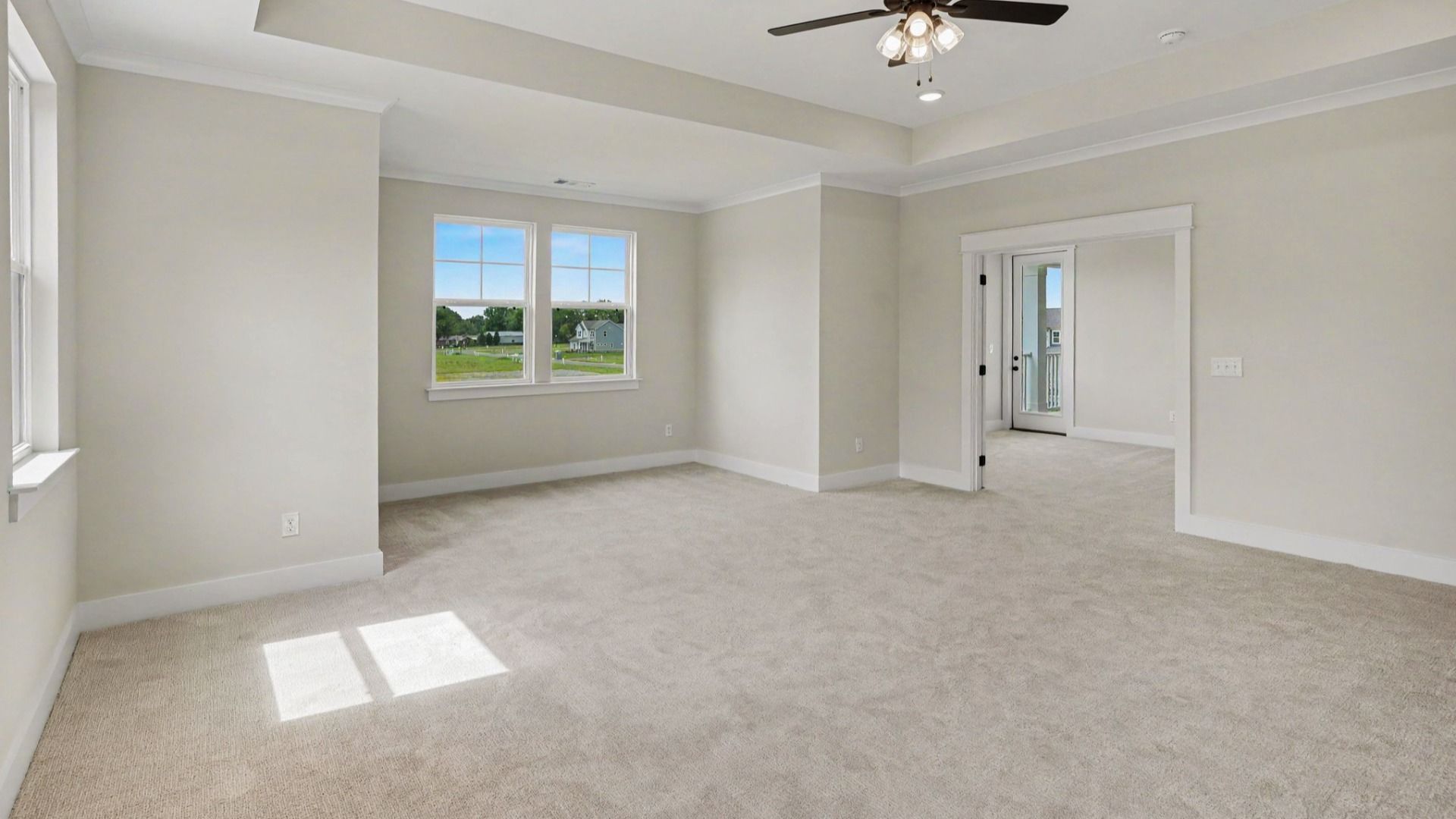 Primary suite with tray ceiling, ceiling fan, and carpet
