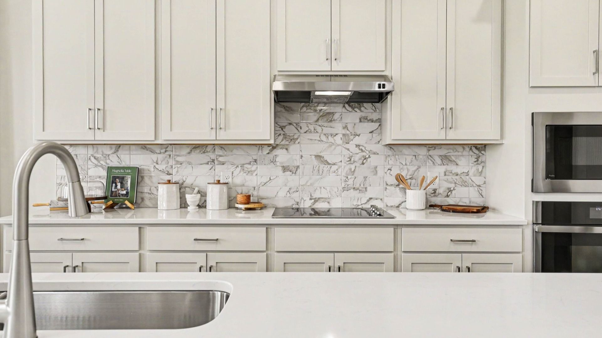 Kitchen with quartz countertops, tile backsplash, and light cabinetry