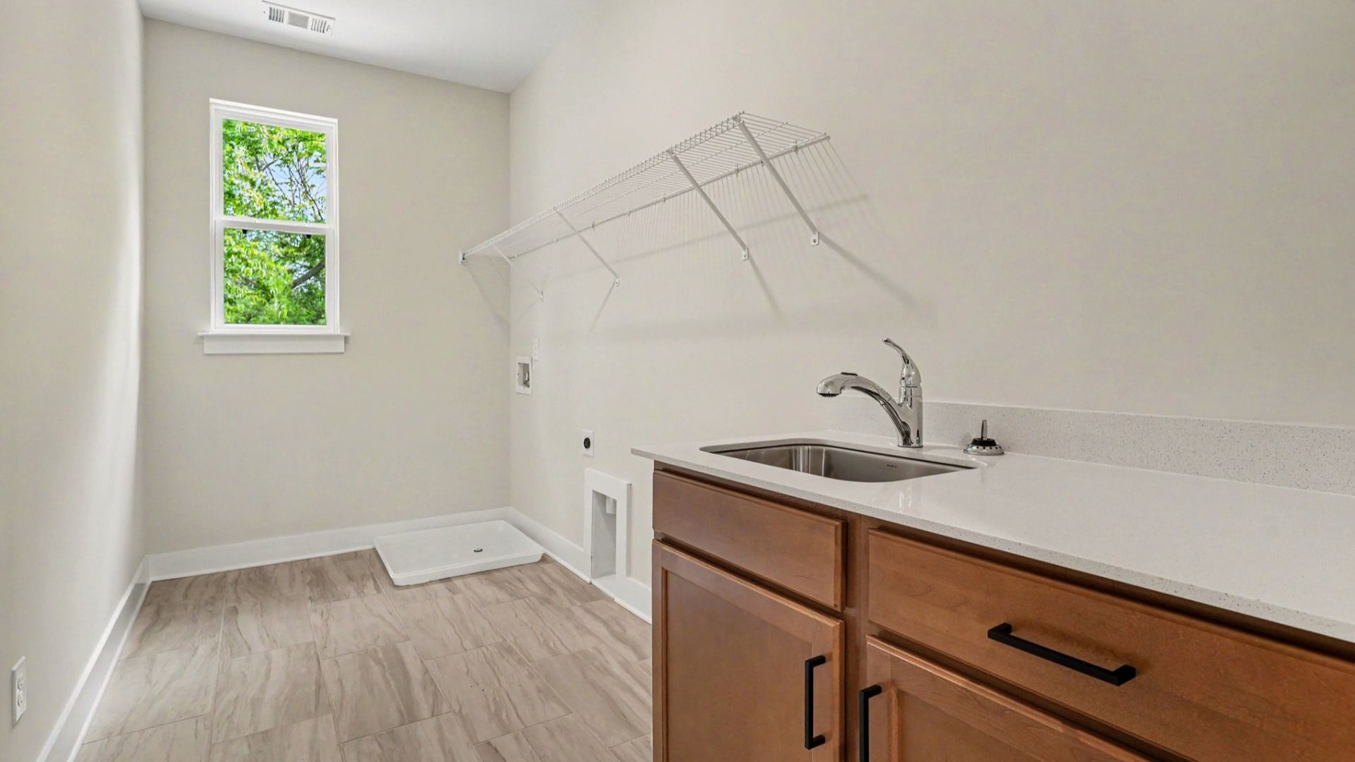 Spacious dedicated laundry room with window, sink, and ventilated shelf