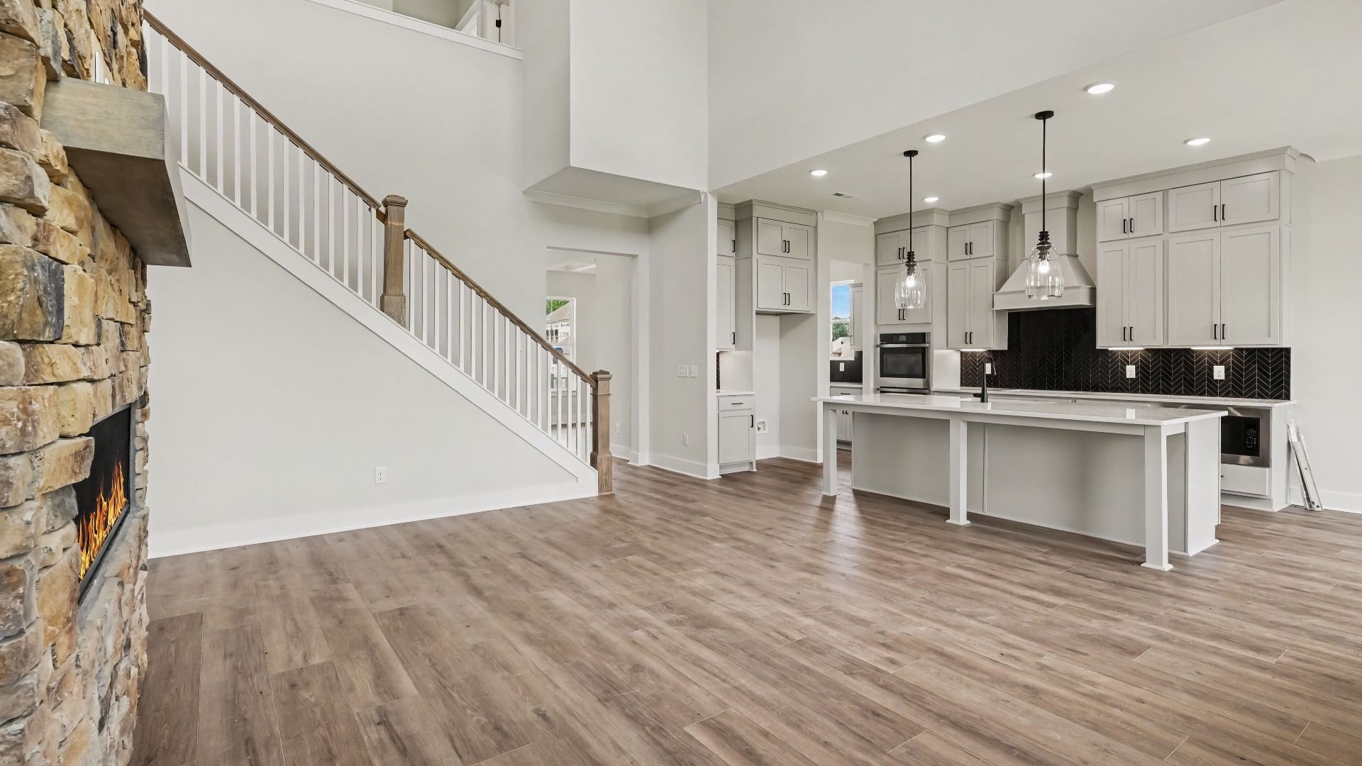 Gathering room with high ceilings, bright natural lighting from windows, and view of kitchen