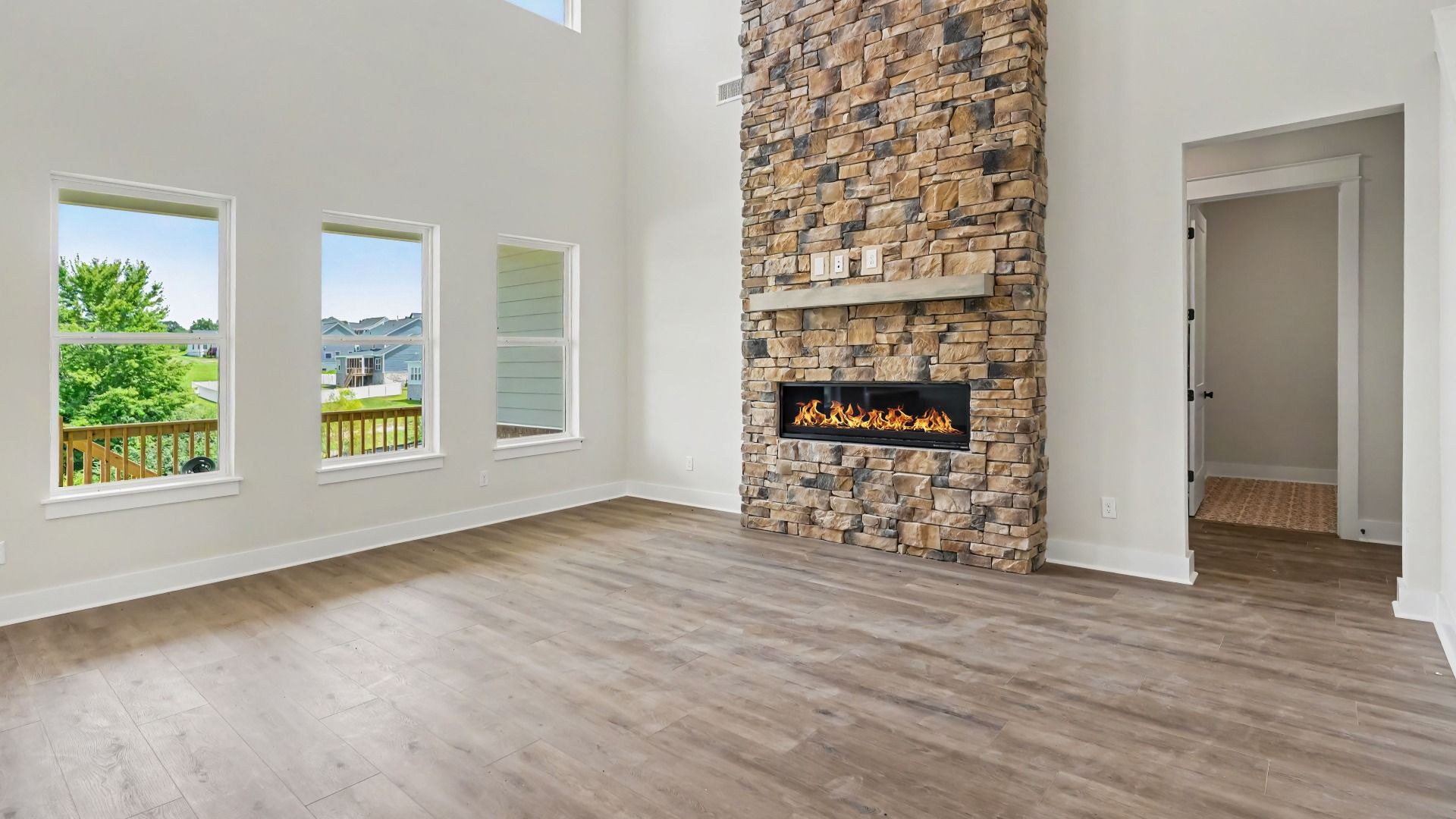 Gathering room with high ceilings, bright natural lighting from windows, and view of kitchen