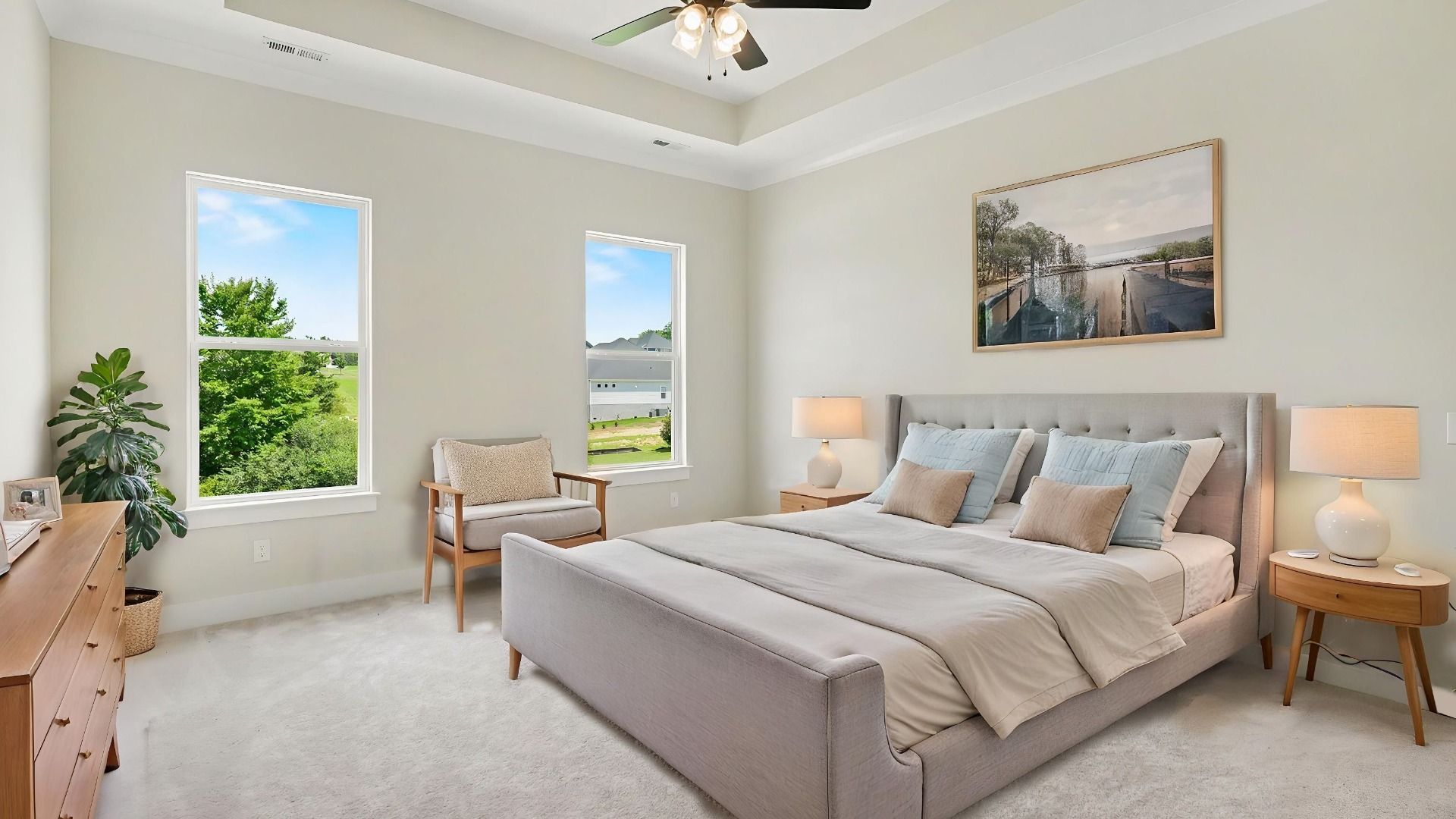 Primary suite with tray ceiling, ceiling fan, and carpet