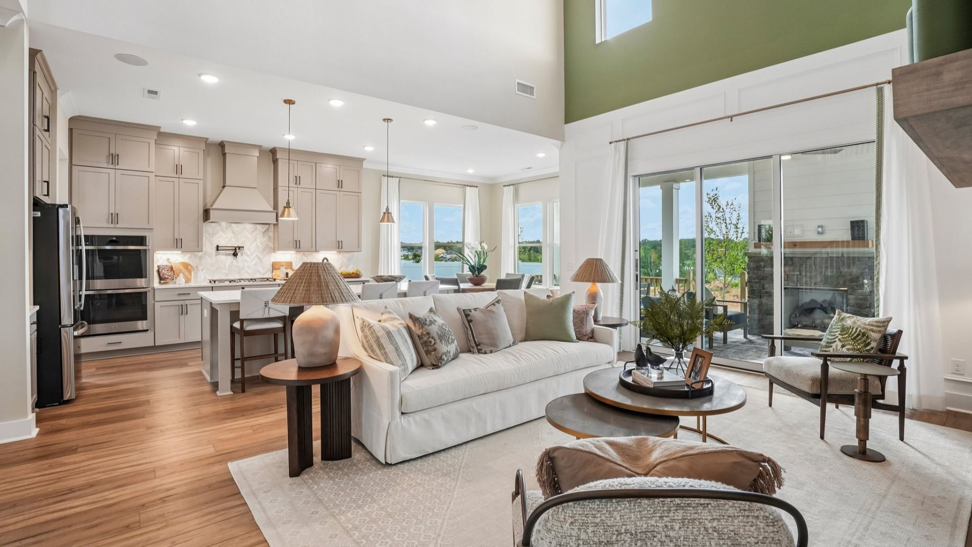 Gathering room with high ceilings, bright natural lighting from windows, and view of kitchen