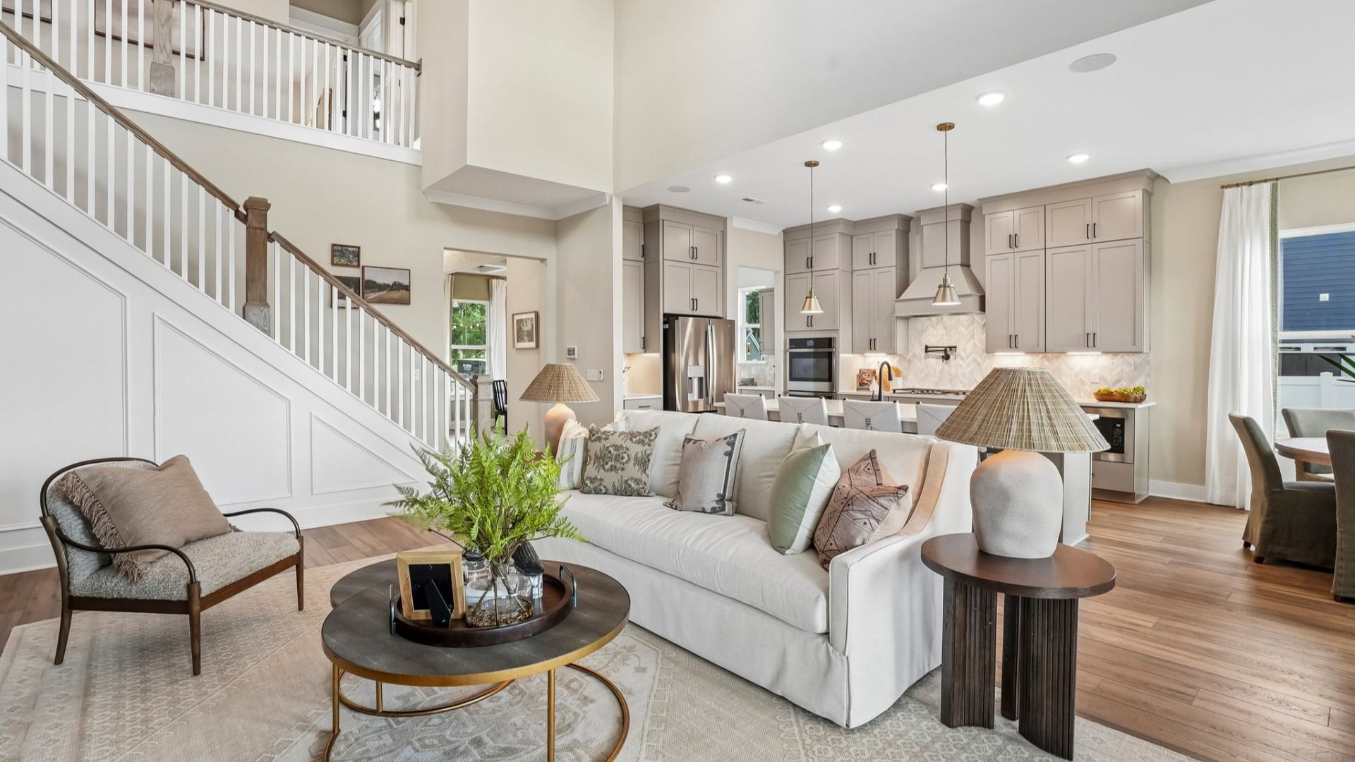Gathering room with high ceilings, bright natural lighting from windows, and view of kitchen