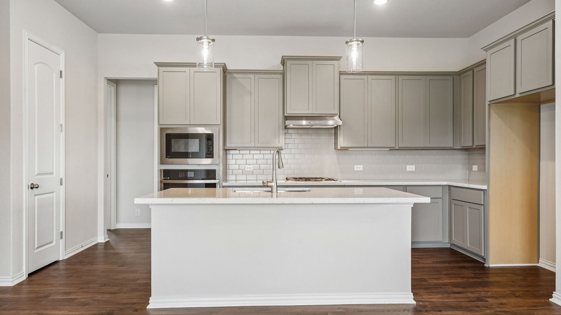 Modern kitchen design features a ceramic tile backsplash, OmegaStone countertops, and a spacious island.