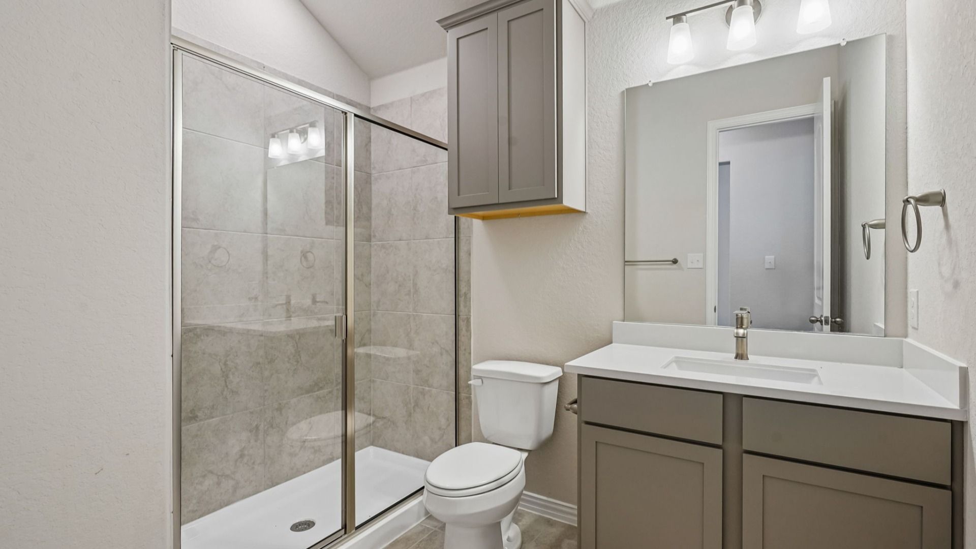 Secondary bath features a stylish vanity and a sleek framed glass shower for a modern touch.