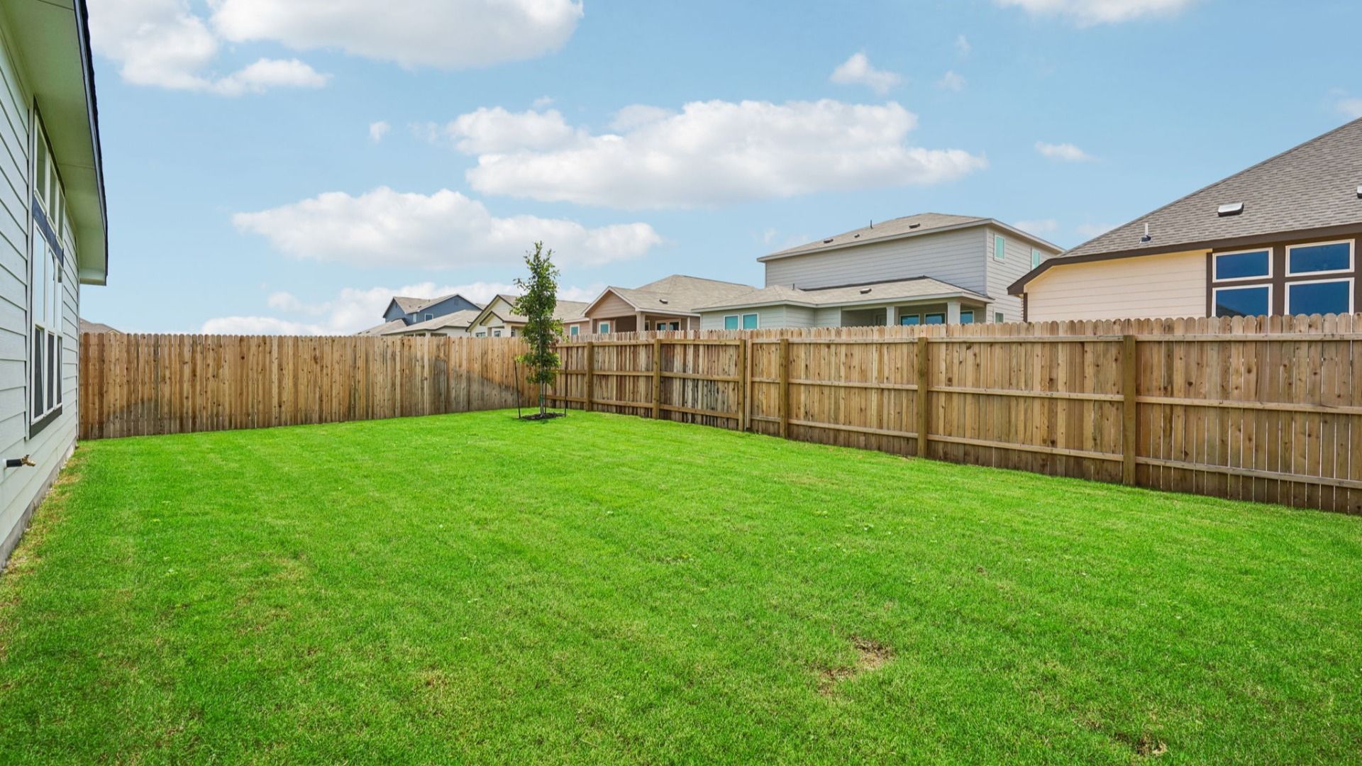 Large backyard features a covered patio and a tree that complements the outdoor space.