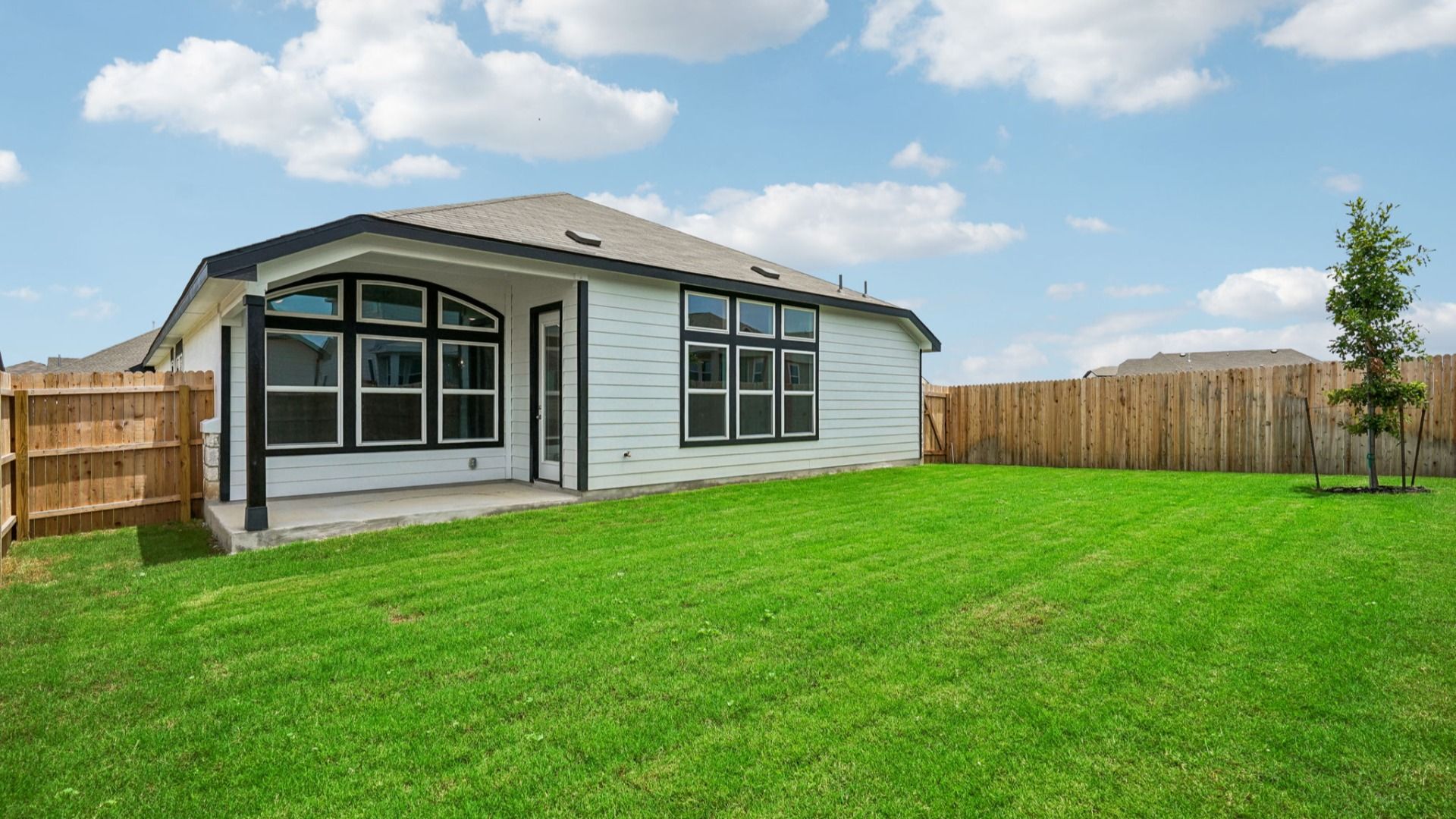 Large backyard features a covered patio and a tree that complements the outdoor space.