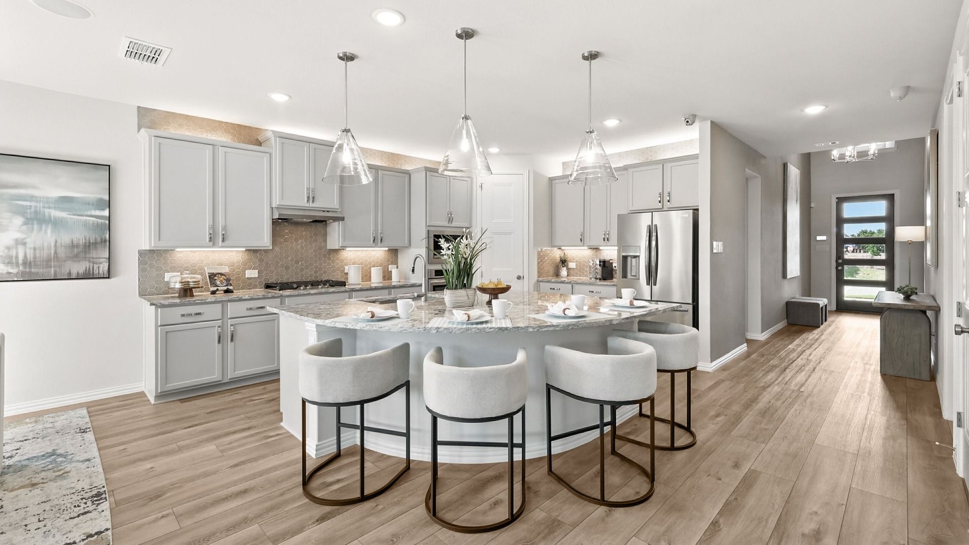Bright open-concept kitchen with oversized island, pendant lighting, and elegant finishes throughout.