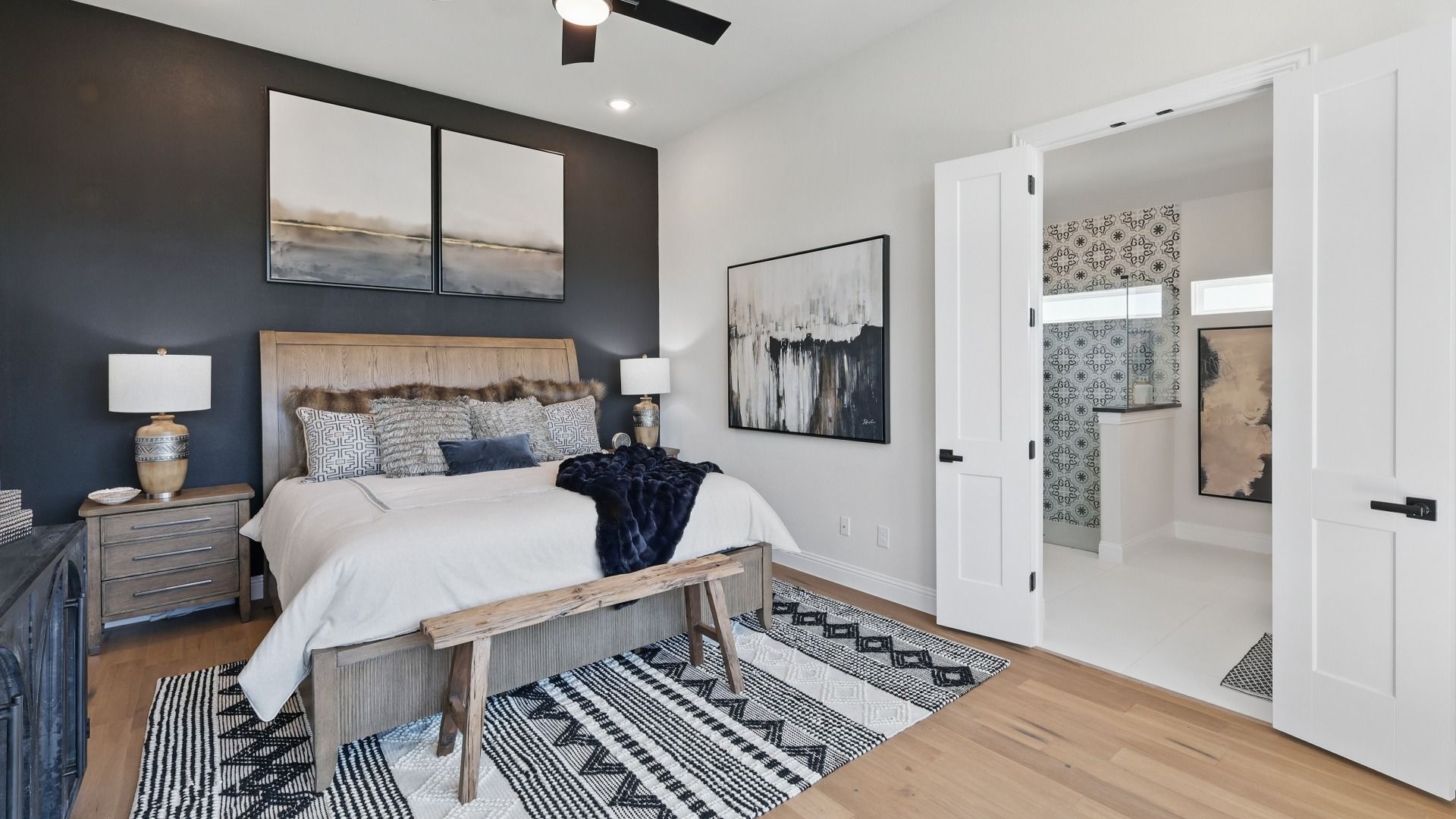 Elegant primary bedroom with a bold accent wall, wood flooring, and direct access to the en-suite bath.