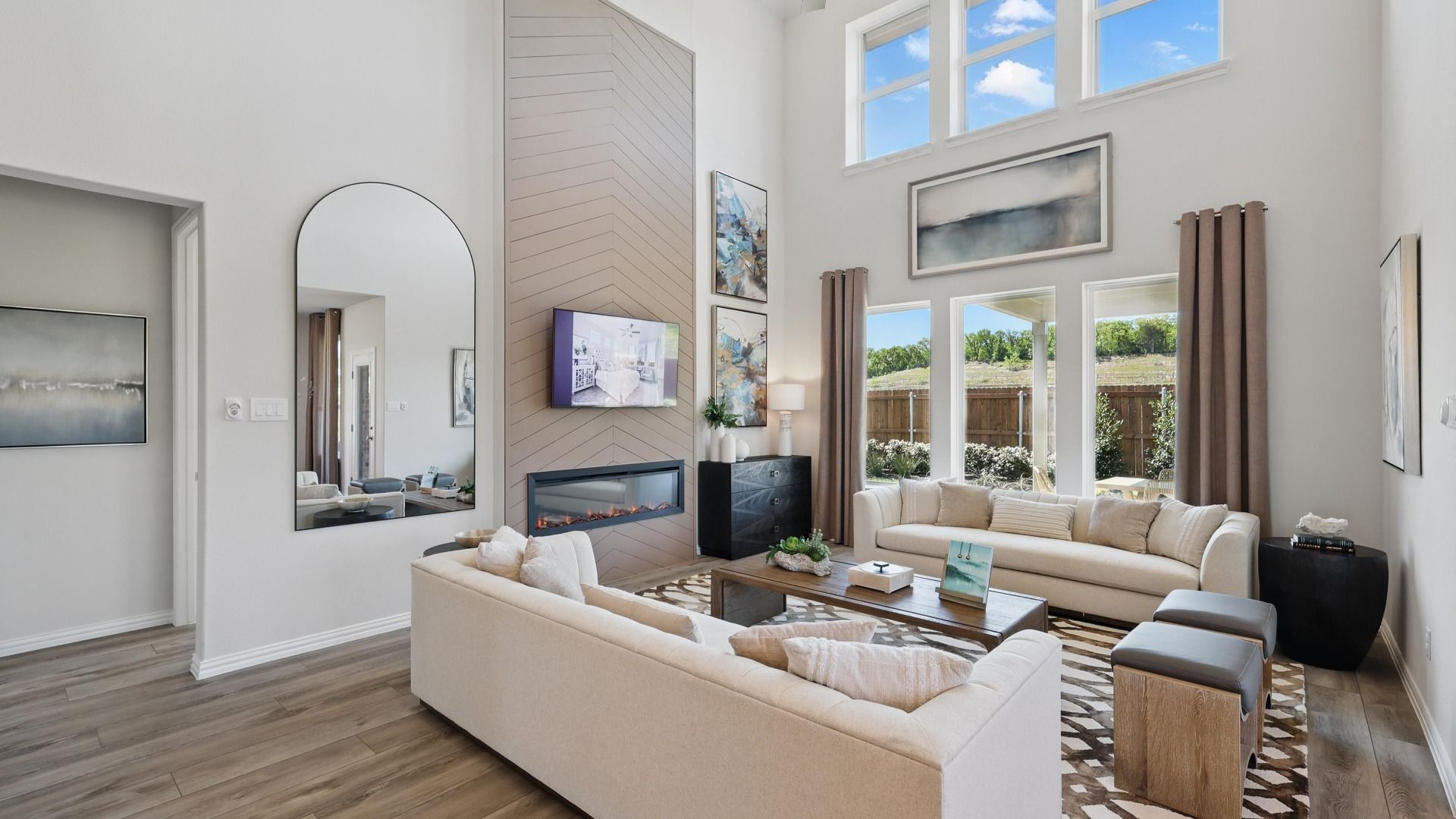 Open-concept living room featuring soaring ceilings, expansive windows, and a modern fireplace feature wall.