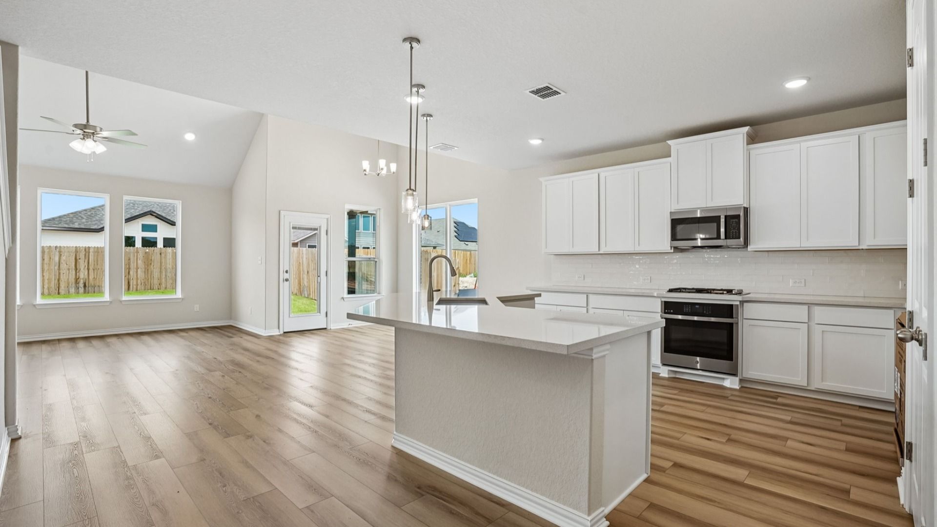 Kitchen features white 42" cabinetry, white/neutral countertops, pendant lighting, and stainless appliances