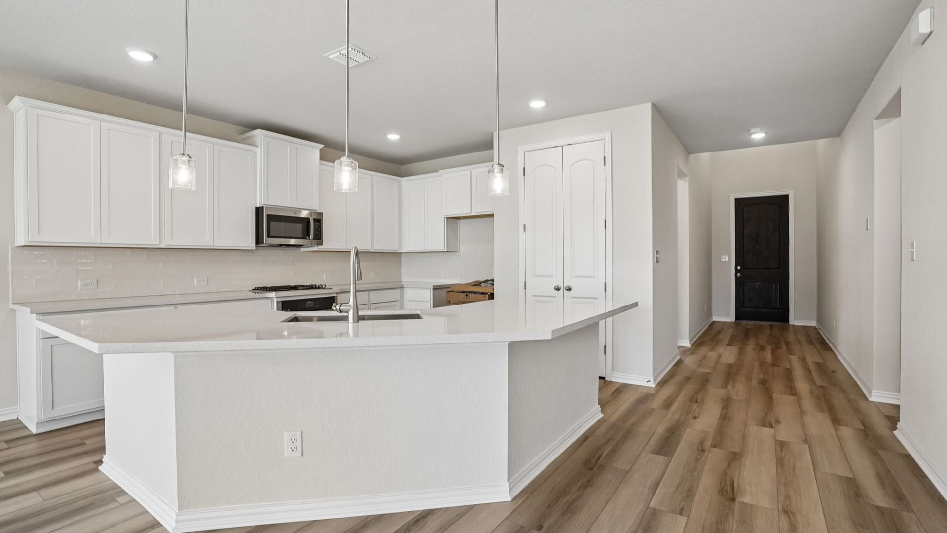 Kitchen features white 42" cabinetry, white/neutral countertops, pendant lighting, and stainless appliances