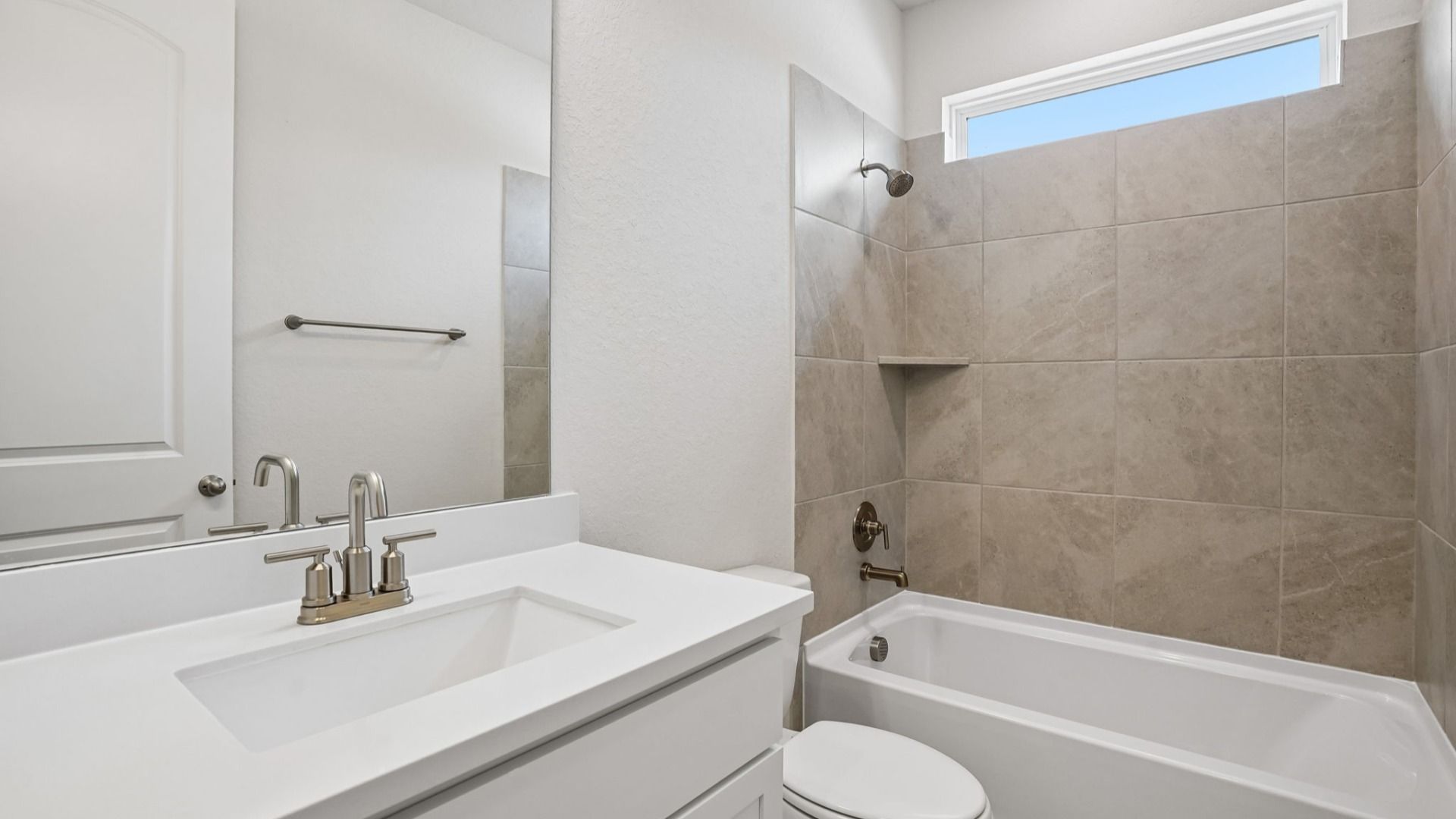 The secondary bathroom features a window that provides natural light, along with a vanity for added convenience and storage.