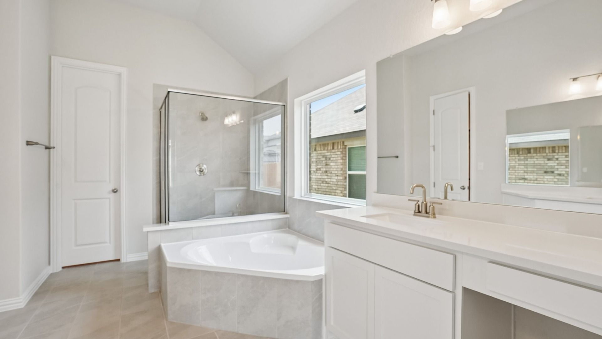 Owner's bath contains standout luxury features including a garden tub, separate vanities, and a framed glass shower.