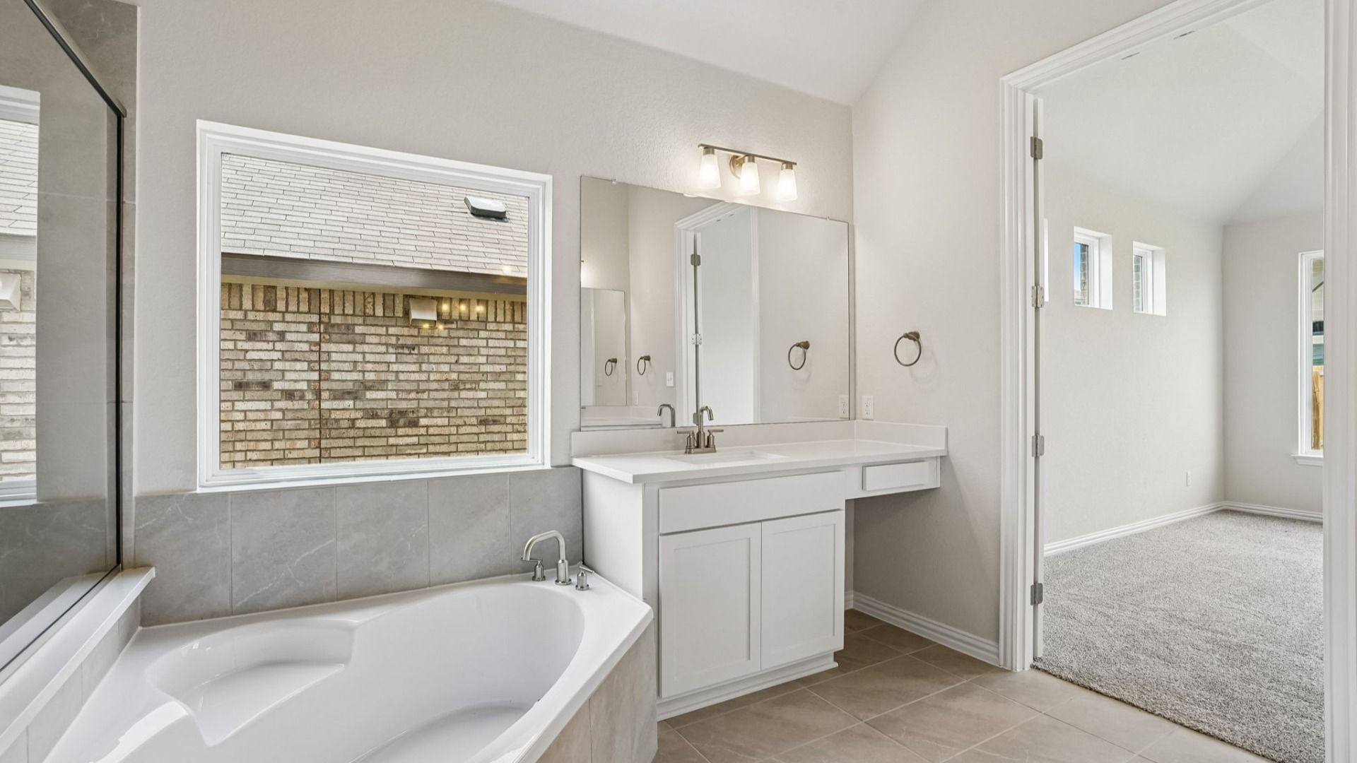 Owner's bath contains standout luxury features including a garden tub, separate vanities, and a framed glass shower.