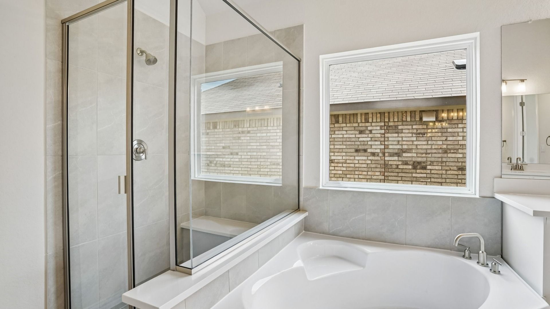 Owner's bath contains standout luxury features including a garden tub, separate vanities, and a framed glass shower.