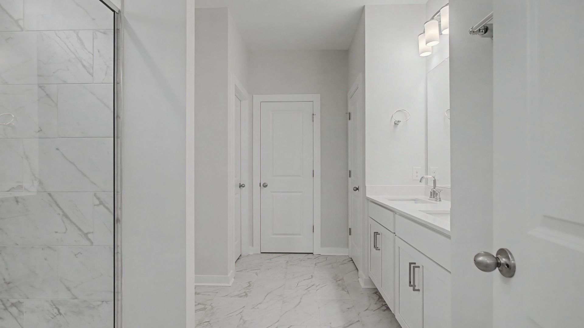 Beautiful and clean white bathroom with quartz countertops and marble-style tile flooring and shower walls