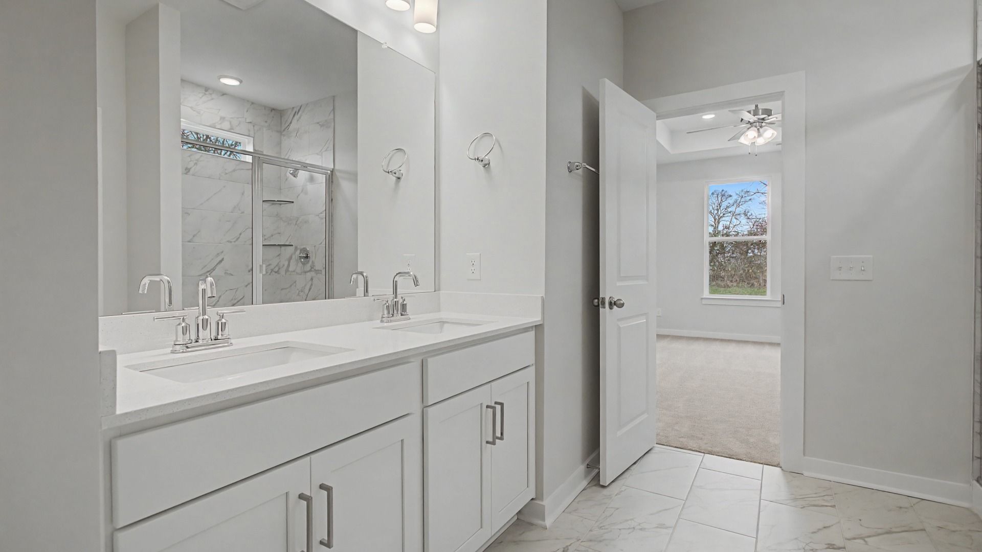 Beautiful and clean white bathroom with quartz countertops and marble-style tile flooring and shower walls