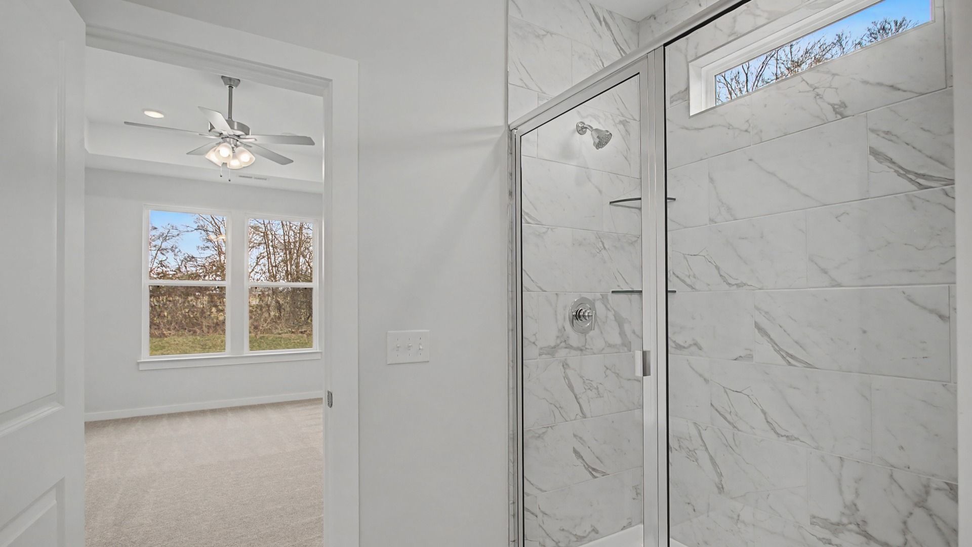 Beautiful and clean white bathroom with quartz countertops and marble-style tile flooring and shower walls