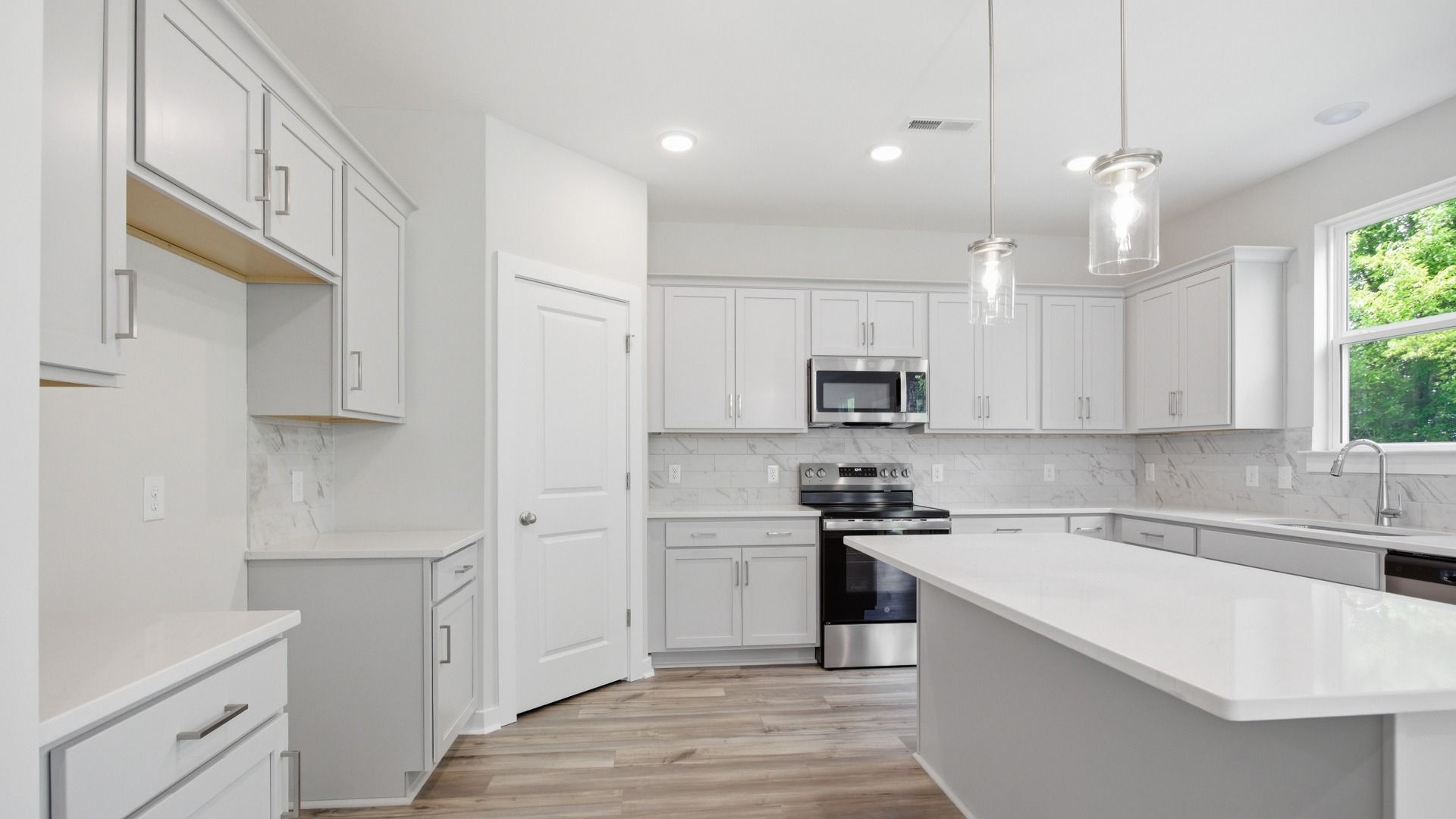 Gorgeous, clean white kitchen with quartz countertops and tile backsplash