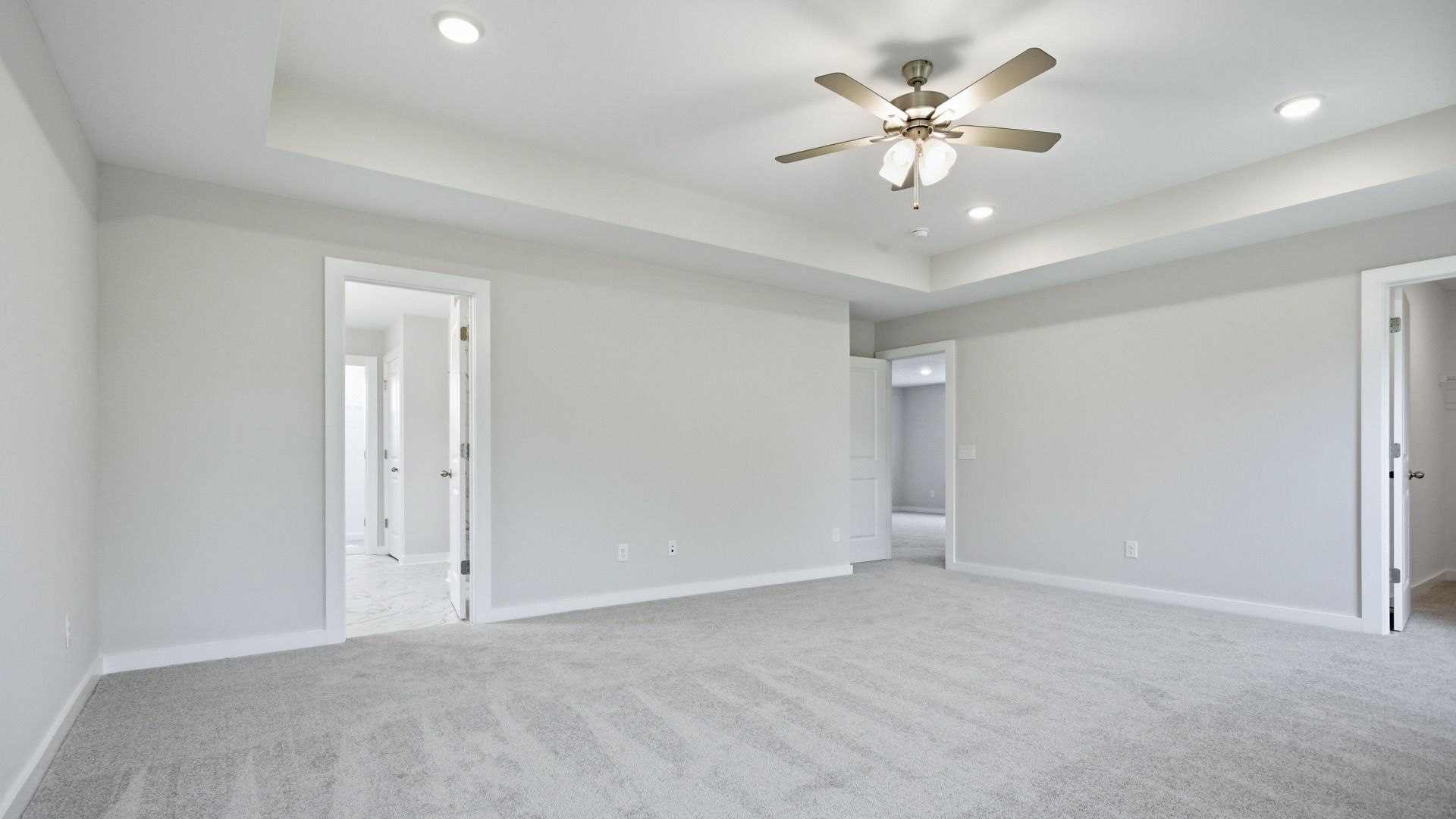 Primary bedroom with closet, en-suite bathroom, and tray ceiling