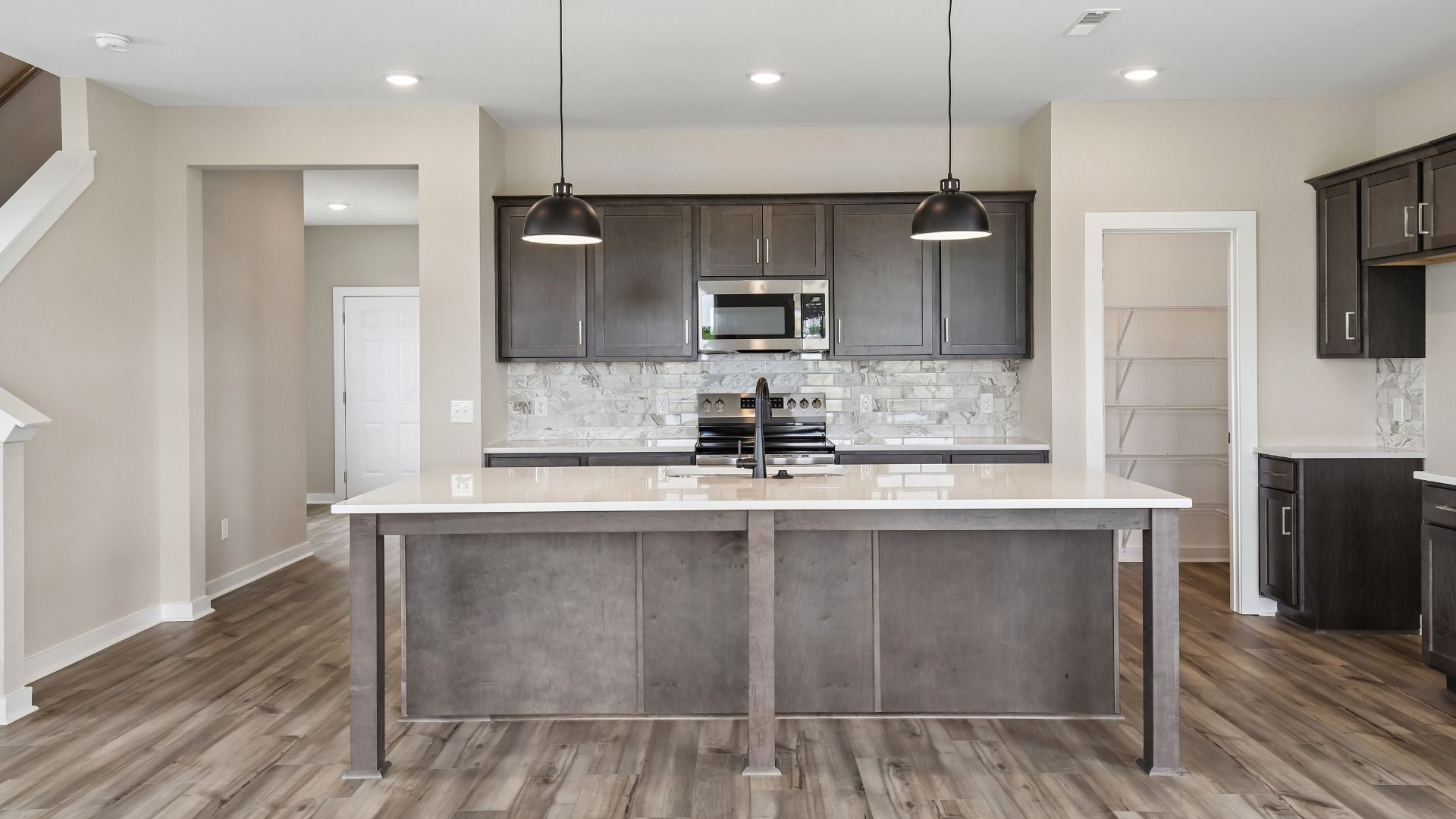 Kitchen with dark cabinetry, quartz countertops, pendant lighting, and tile backsplash