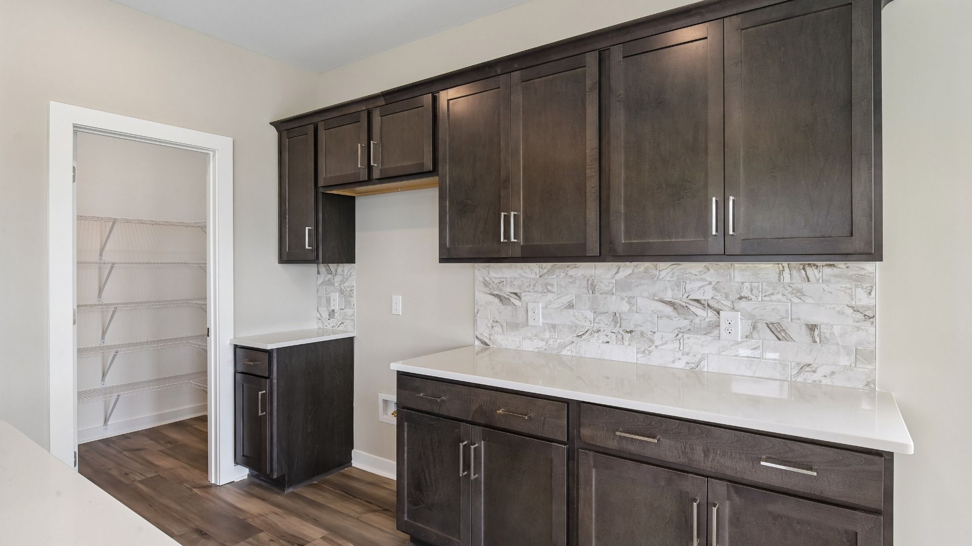 Kitchen with dark cabinetry, quartz countertops, and tile backsplash