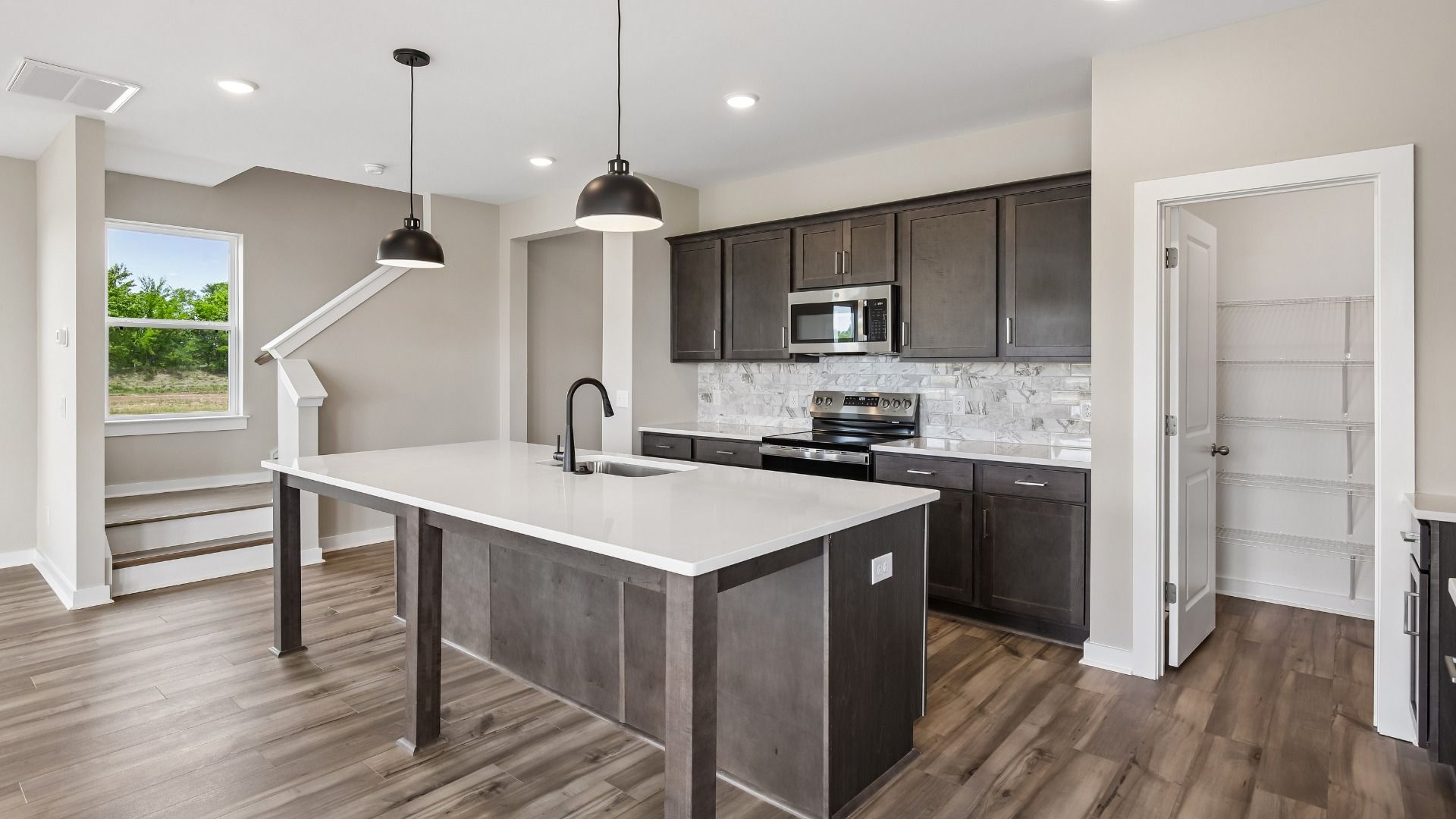 Kitchen with dark cabinetry, quartz countertops, pendant lighting, and tile backsplash