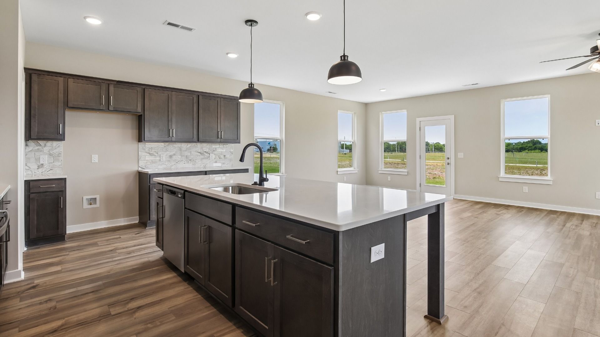 Kitchen with dark cabinetry, quartz countertops, pendant lighting, and tile backsplash