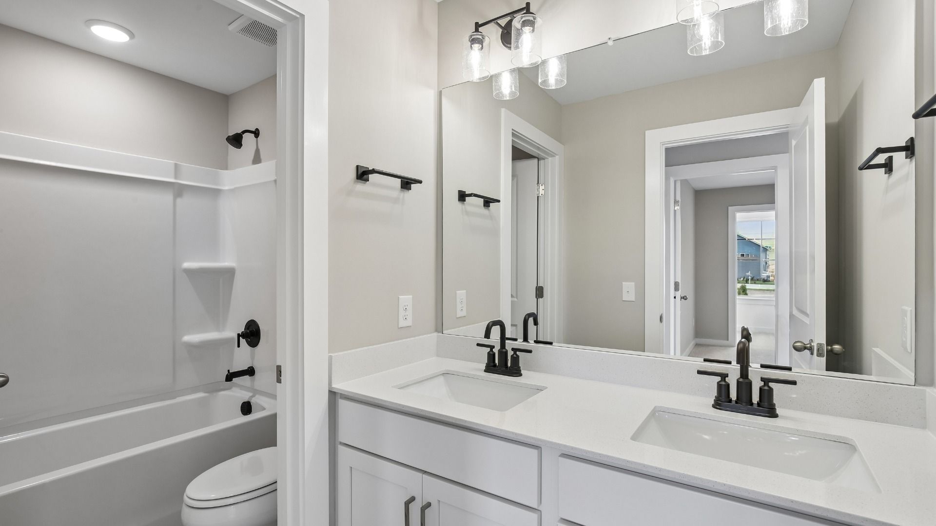 Secondary bathroom with dual vanity and door to shower and toilet