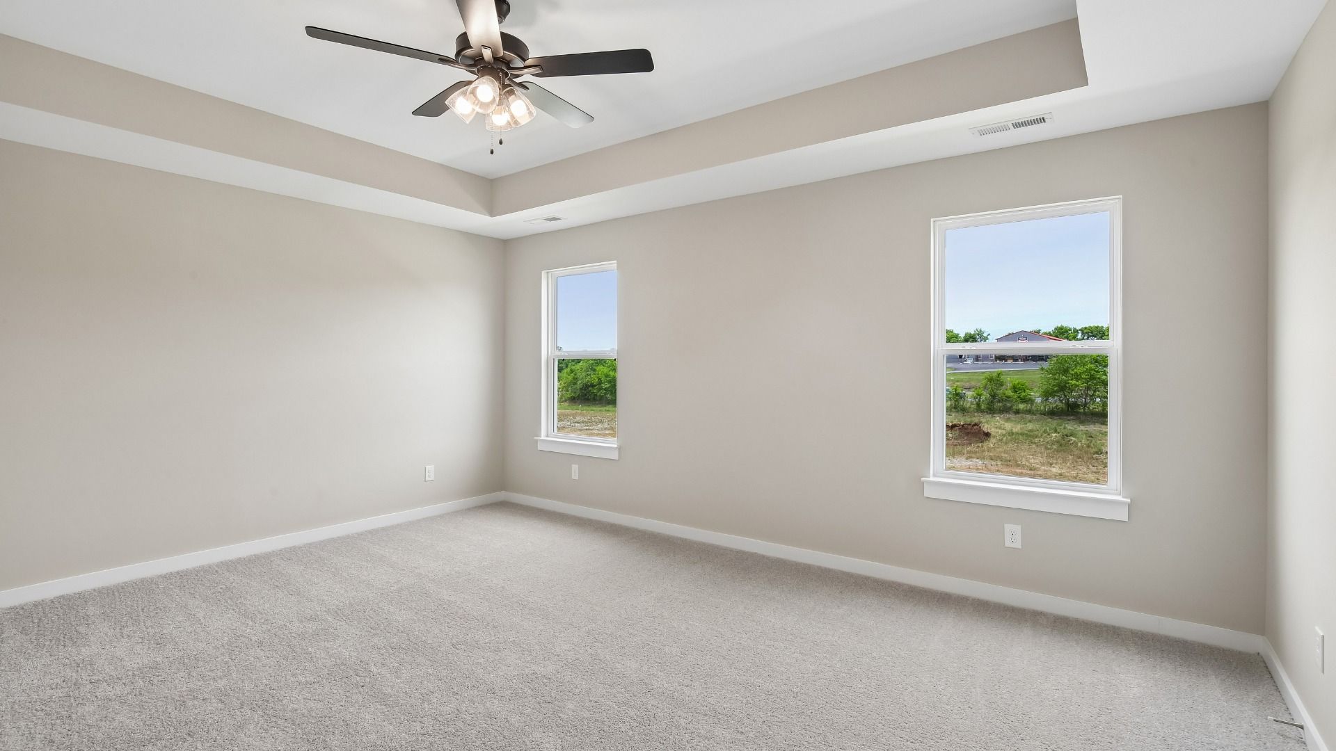 Bedroom with tray ceiling, windows, and en-suite primary bathroom