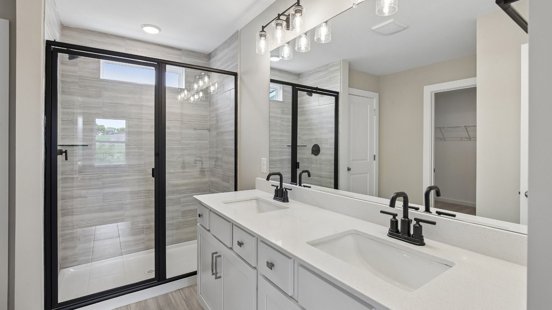 Bathroom with tile flooring and shower with glass enclosure, along with dual vanity