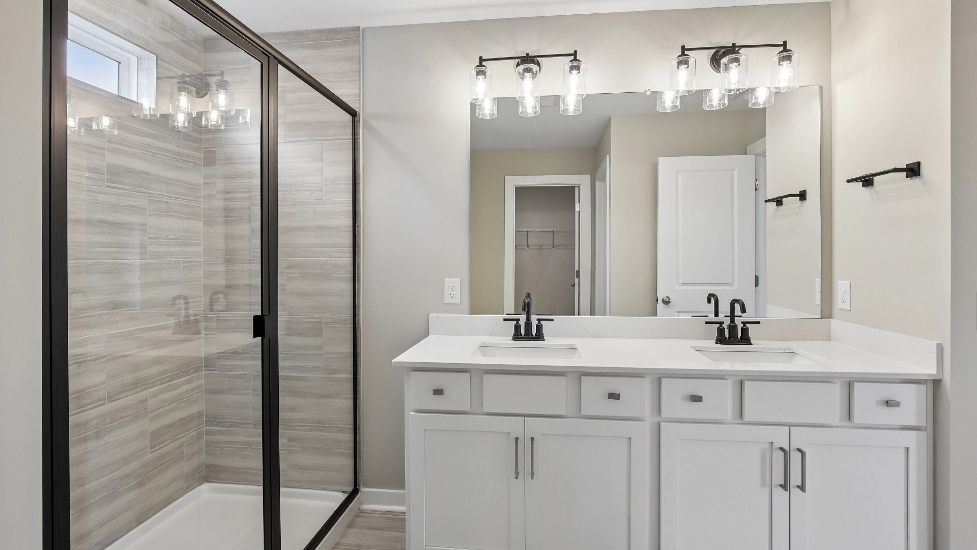 Bathroom with tile flooring and shower with glass enclosure, along with dual vanity