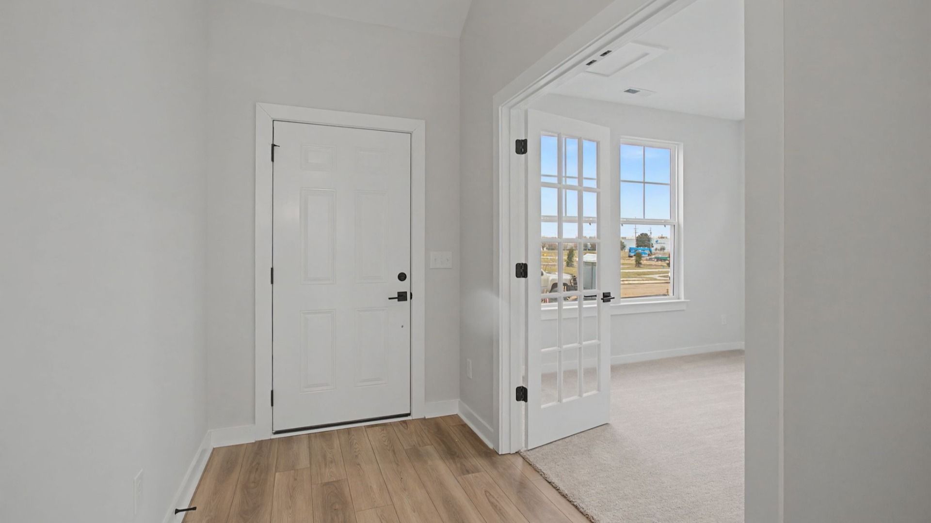 Entry to home with light LVP flooring and glass doors to study