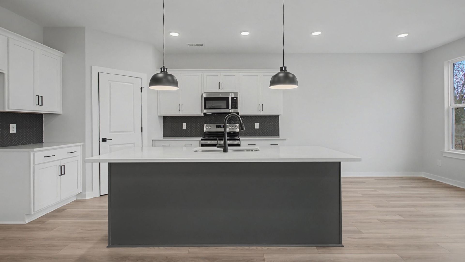 Kitchen with white cabinets and quartz countertops, tile accent backsplash, and pendant lighting