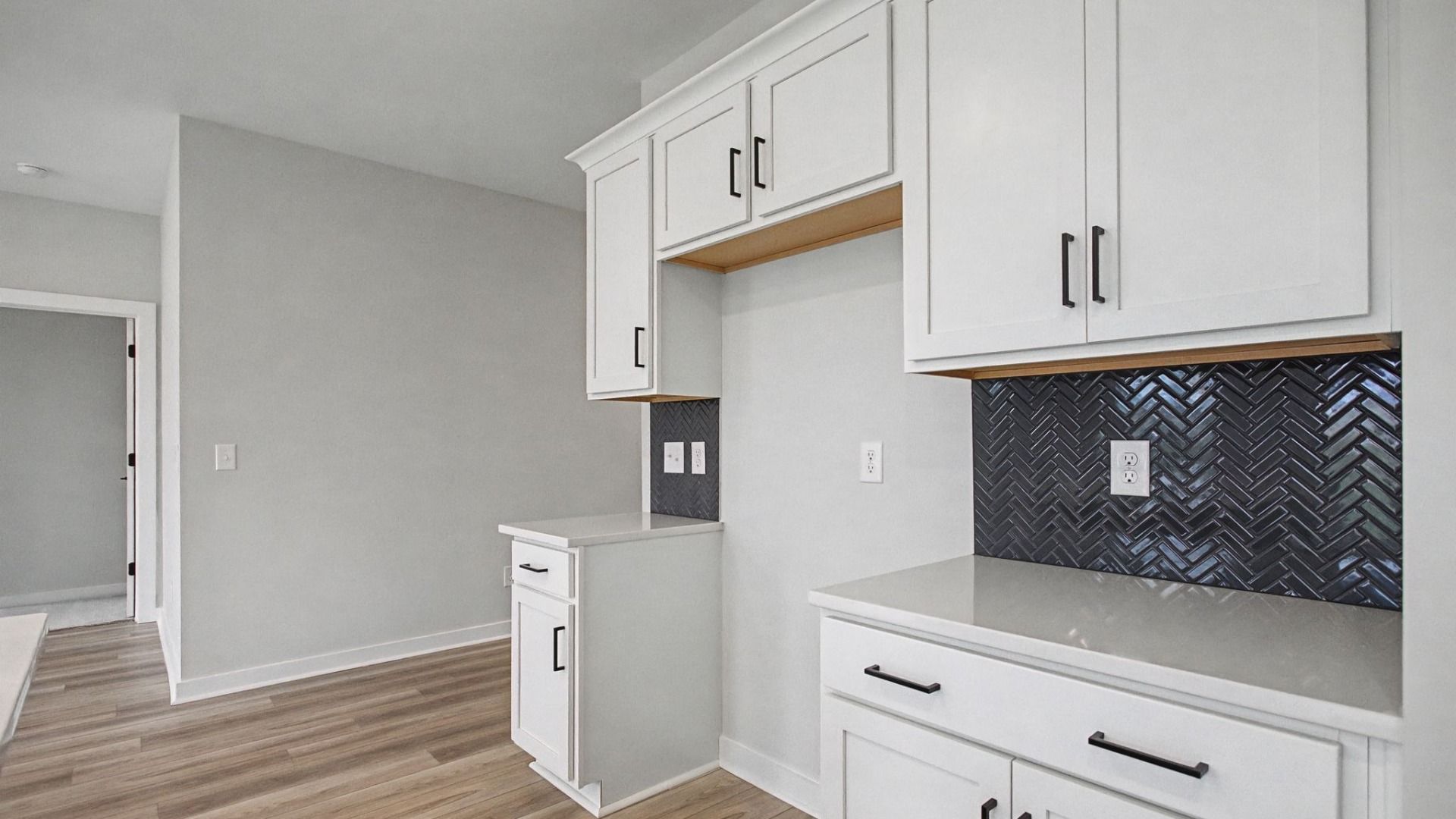 Kitchen with white cabinets and quartz countertops, tile accent backsplash, and pendant lighting