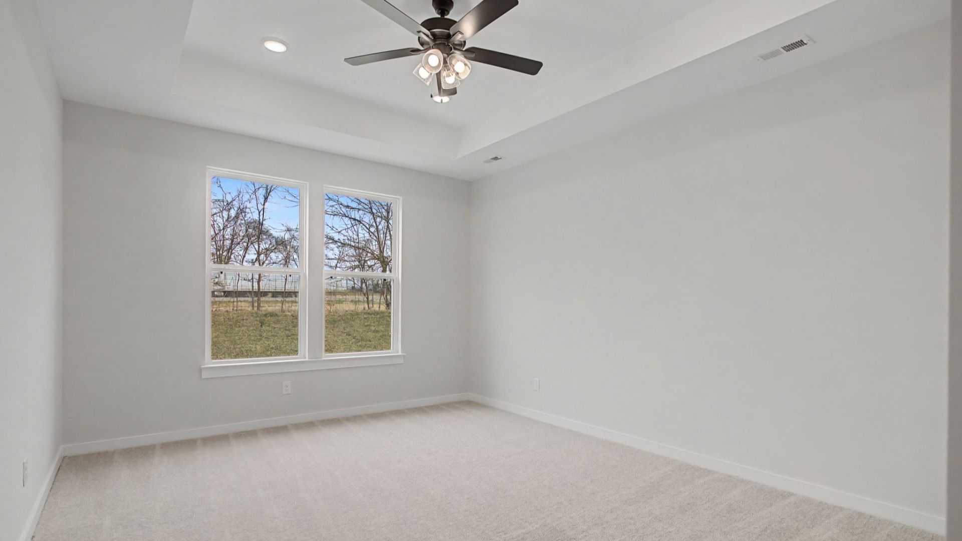 Primary bedroom with tray ceiling and ceiling fan