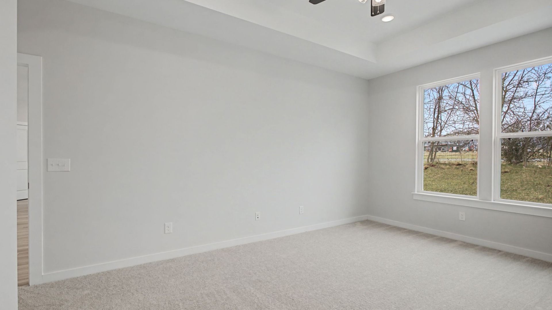 Primary bedroom with tray ceiling and ceiling fan, and door to living area