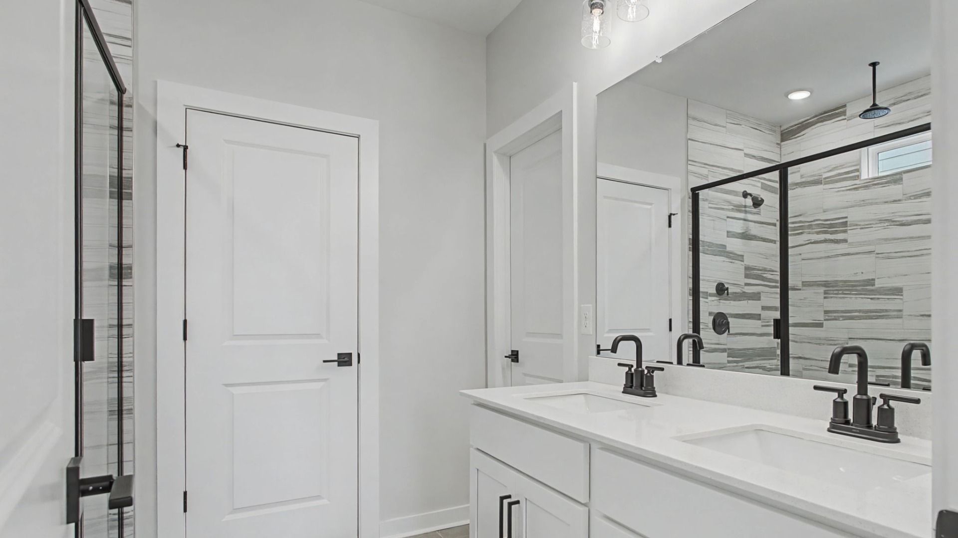 Bathroom with dual sink vanity, quartz countertop, and tiled floors and shower