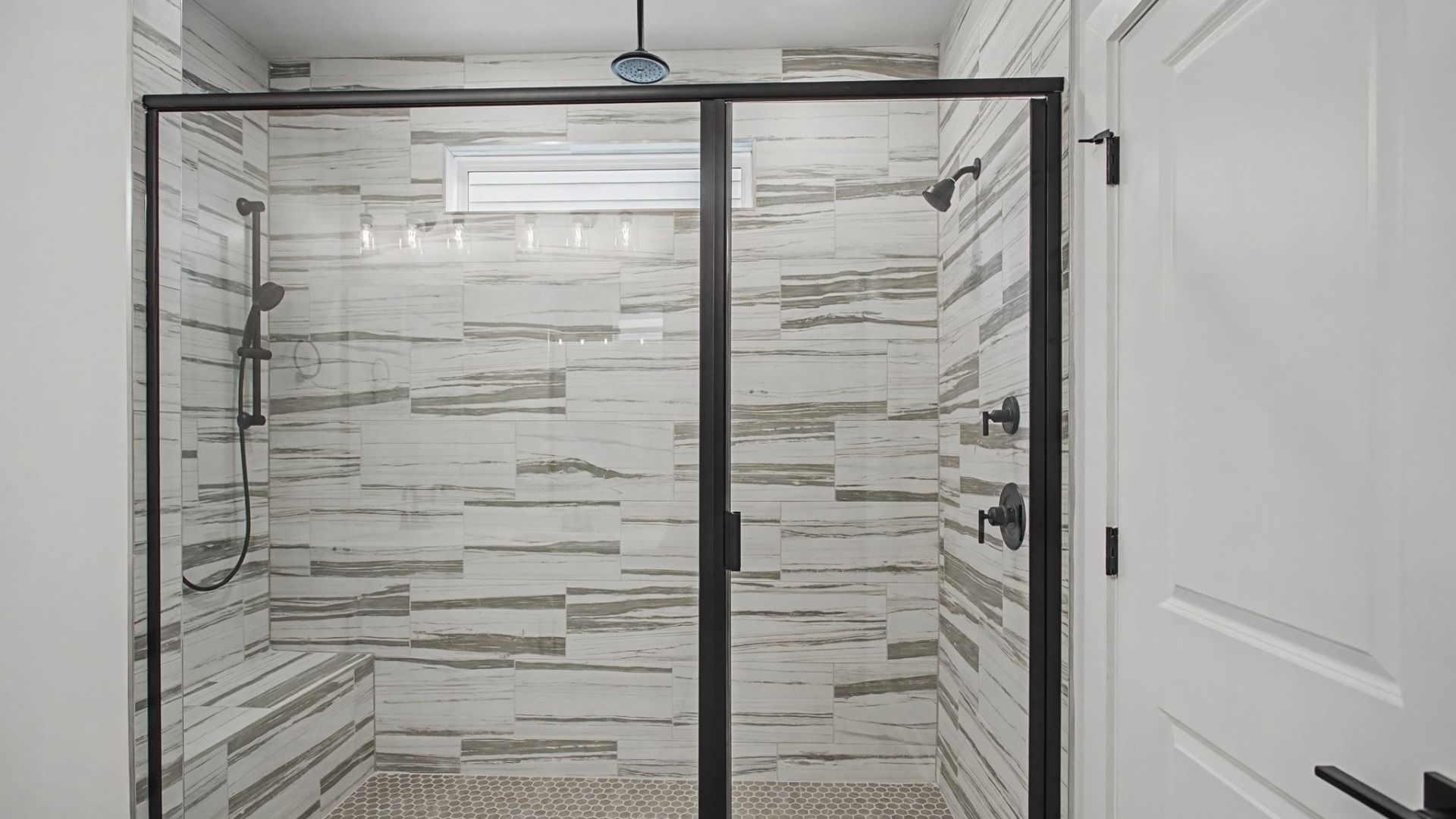 Luxury tiled walk-in shower with glass doors and multiple shower heads