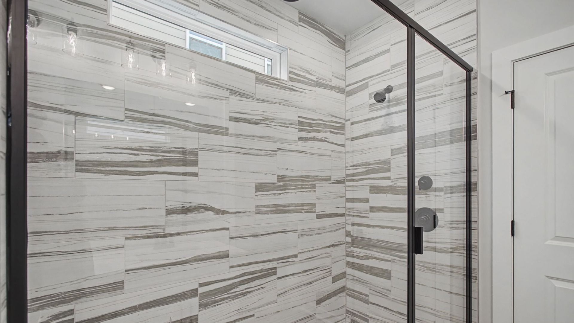 Luxury tiled walk-in shower with glass doors and mutiple shower heads