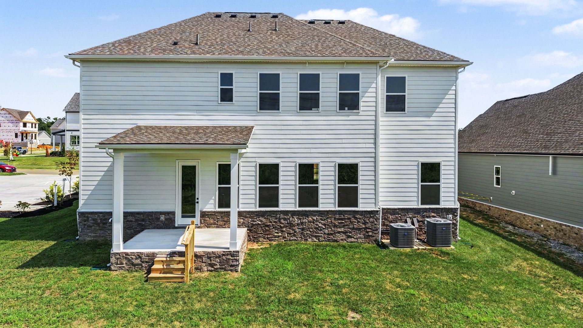 Back of home with covered porch and sodded backyard