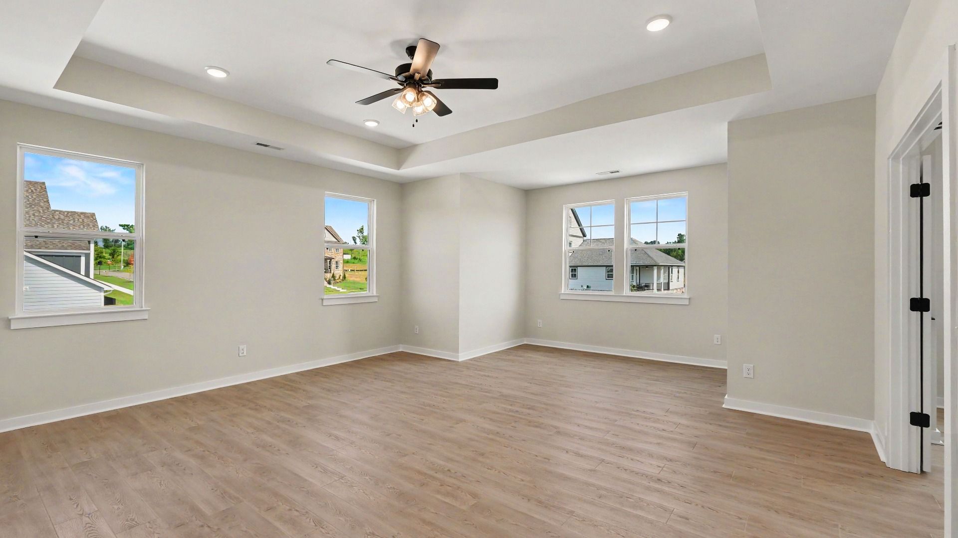 Second Floor primary bedroom with hardwood flooring, tray ceiling, and view of connected private study