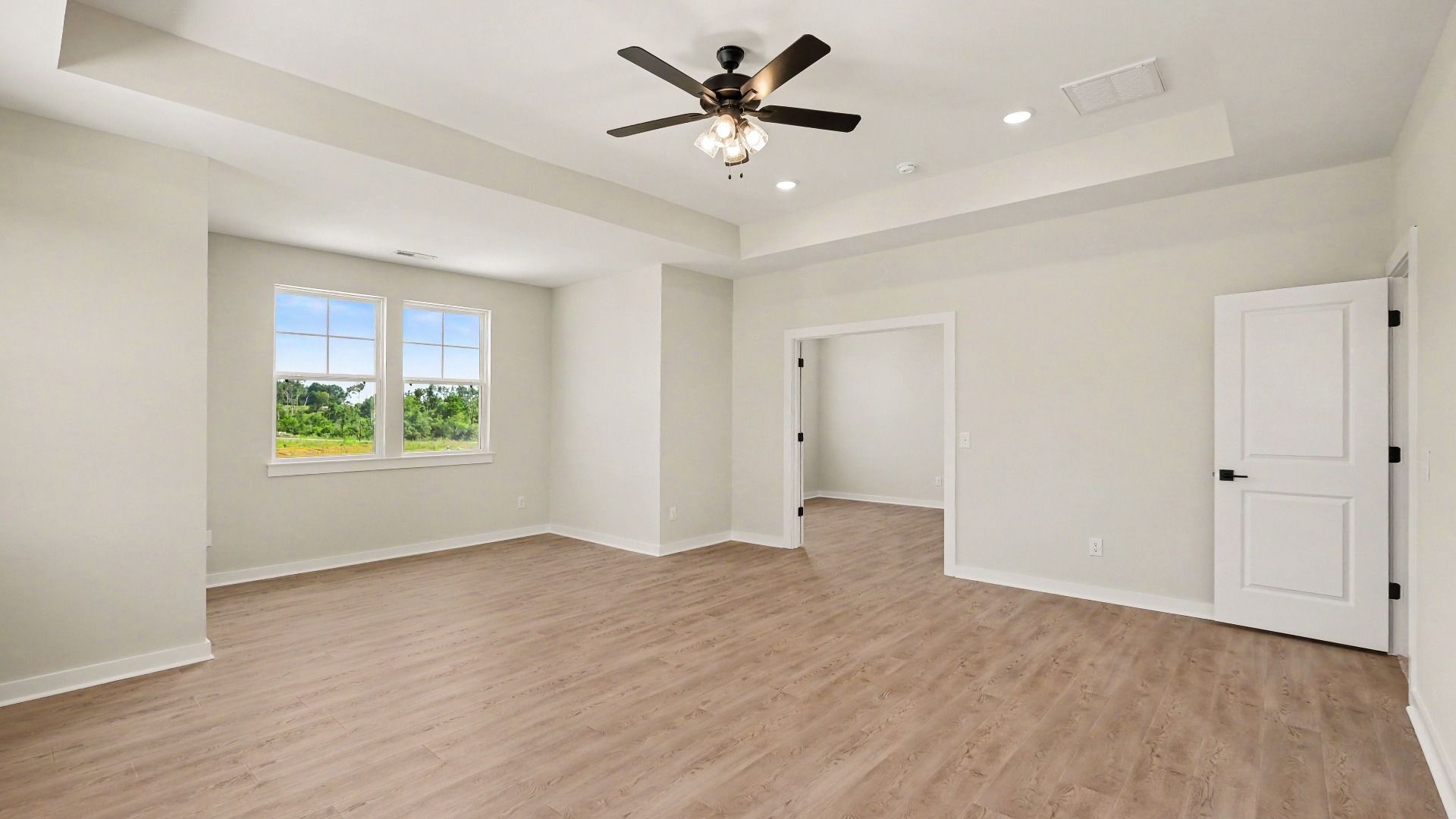 Second Floor primary bedroom with hardwood flooring, tray ceiling, and view of connected private study